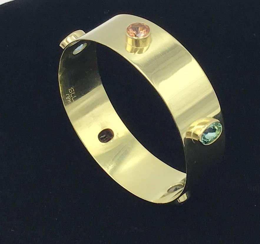 This Multi Gem Bangle in 18 Karat Gold includes Orange Garnet, Mint Green Tourmaline, Tanzanite, Pink Tourmaline and Aquamarine.

This bangle is available in 3 different widths and looks amazing when worn stacked. 

It is also available for custom