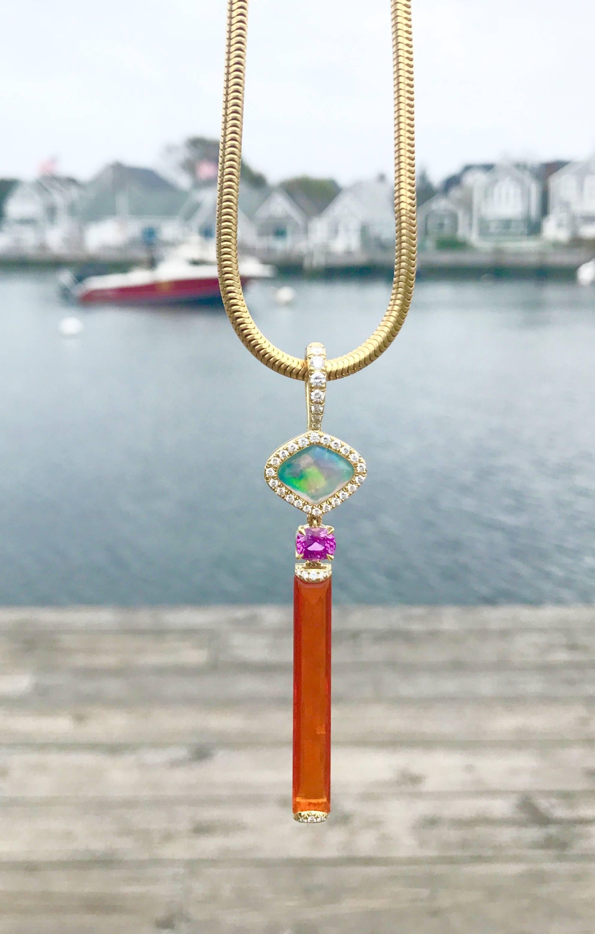 The milky Water Opal is surrounded by Diamonds on a beautiful bale that acts as a clasp for attaching to any necklace of your choice. A deep pink Spinel hangs between the Water Opal and a long rectangular Fire Opal, which is capped at both ends with