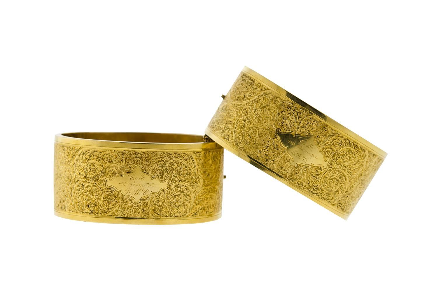 Beautiful pair of Victorian 14 karat yellow gold stiff hinged bangle cuff bracelets. Measuring 1 1/8” wide. Very fine detailed engraving on both sides. No denting. One bracelet has small rub mark on the rim. Each bracelet has one gold safety chain.