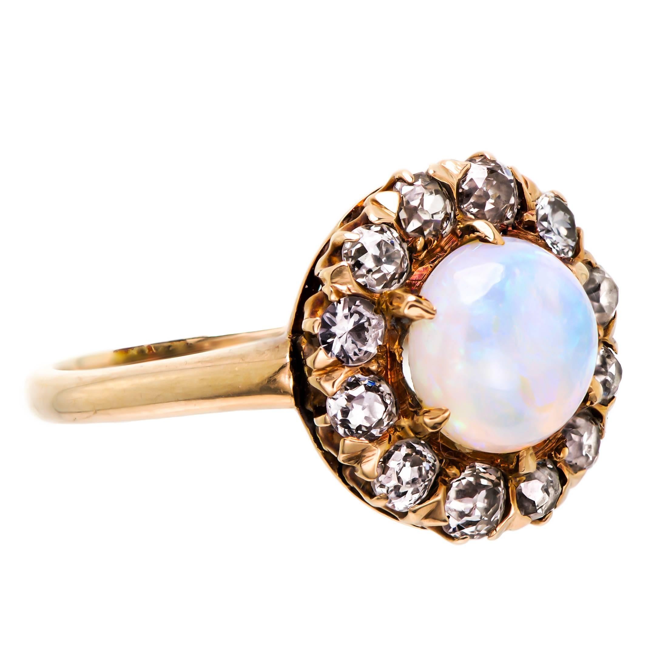 Circa 1900 Victorian opal diamond and yellow gold ring set with one (1) approximately 7mm round cabochon opal prong set second accented by twelve (12) Old European Cut diamonds approximately 0.05cts each for an approximate total of 0.60cts. 