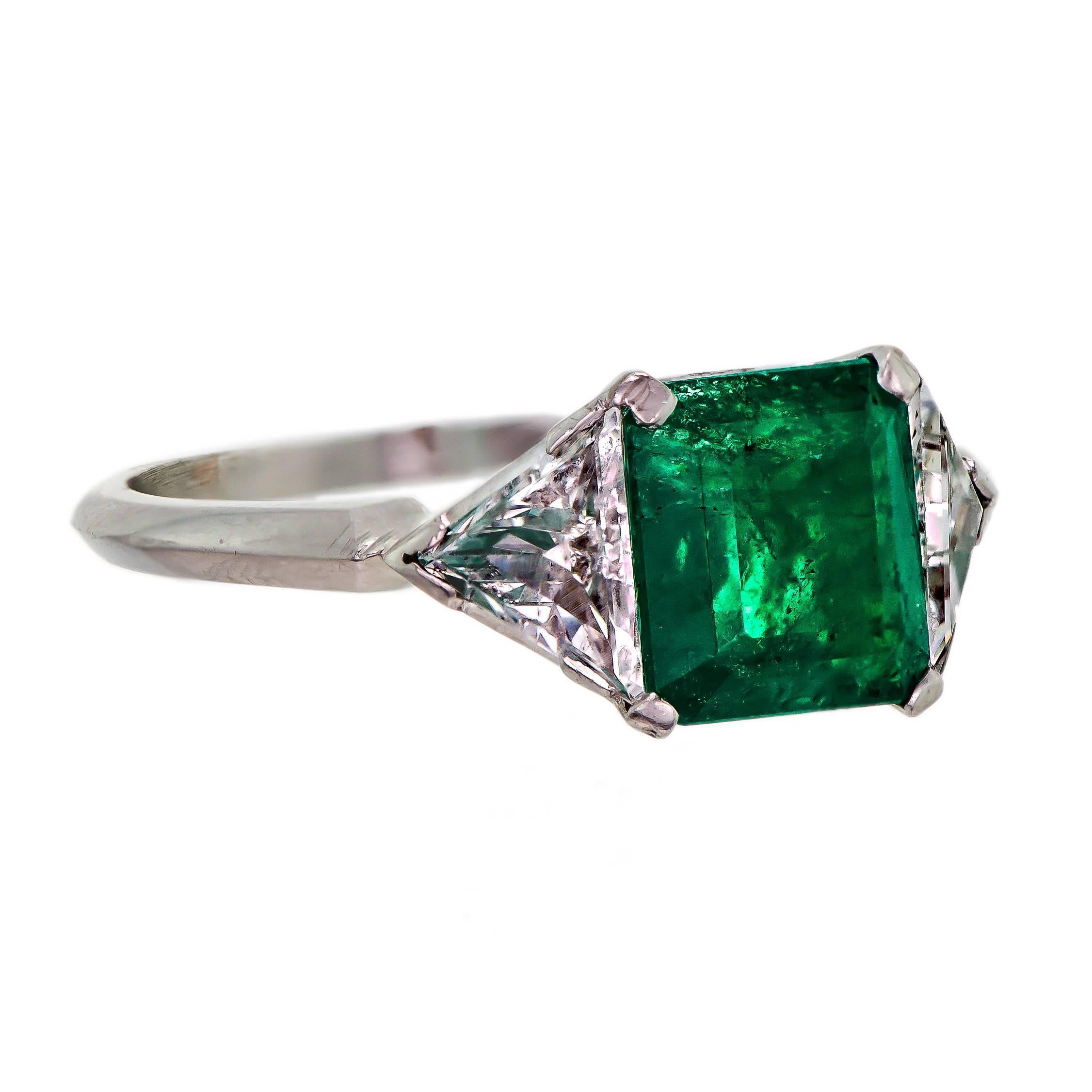 Circa 1930 platinum emerald diamond ring set with one (1) emerald cut emerald measuring approximately 7.9mm length by 7.1mm width and weighing approximately 1.0 ct as measured in the mount further accented by two (2) triangular cut diamonds