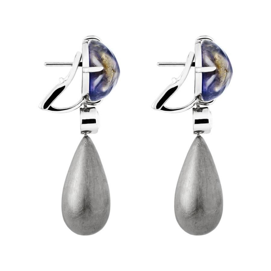 These sophisticated drop earrings feature two half carat diamonds (0.5 ct, H SI) and modern pyramid shaped Iolite cabochons (12 x 12 mm). The earrings, which are crafted in brushed 18 karat rhodium-plated white gold, are also available in yellow