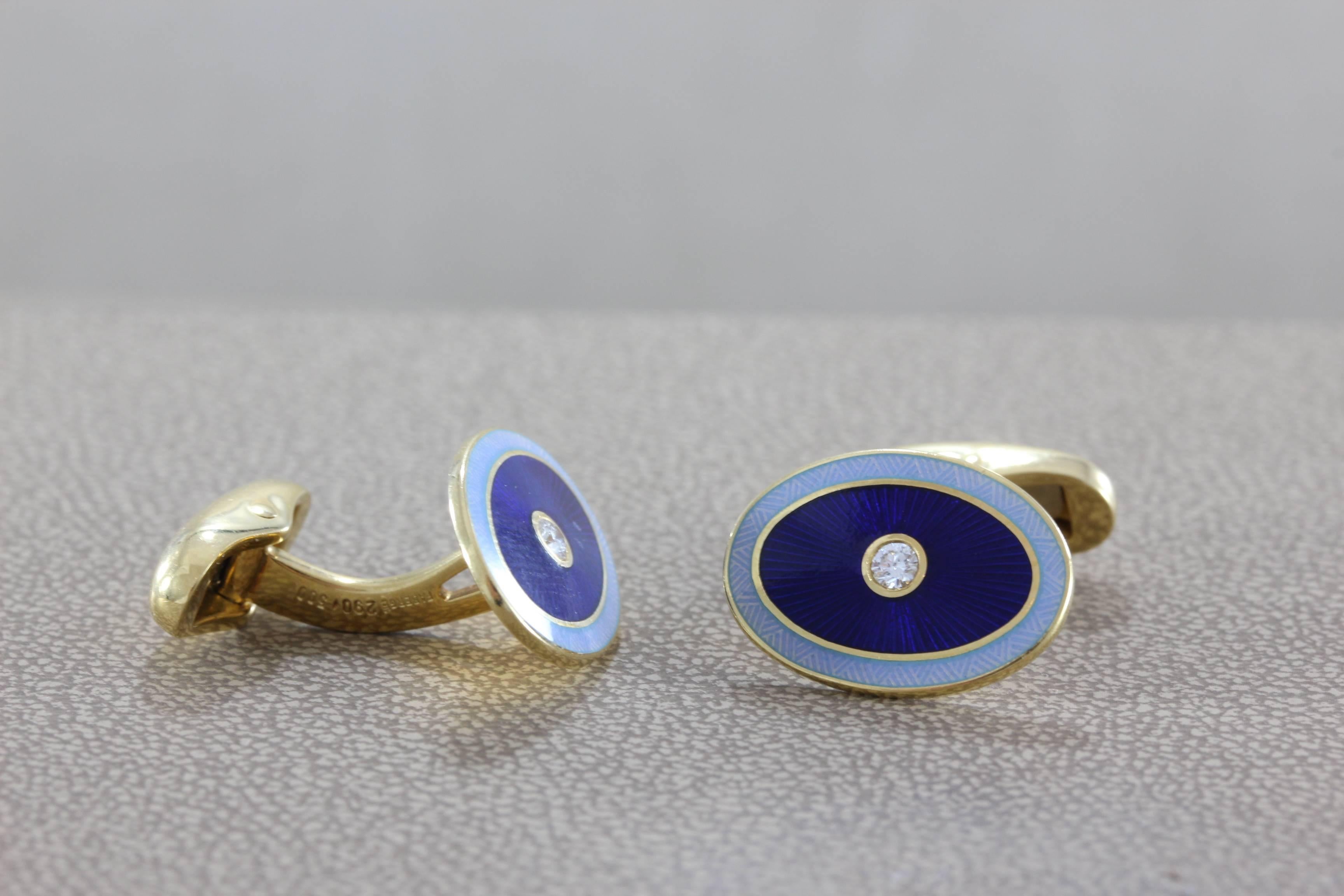 A pair of modern Fabergé cufflinks made in Germany featuring world class enamel as seen in the classic imperial Russian pieces. A round cut diamond centers each cuff, set in 18K yellow gold. (minor damage to enamel on one cuff)
