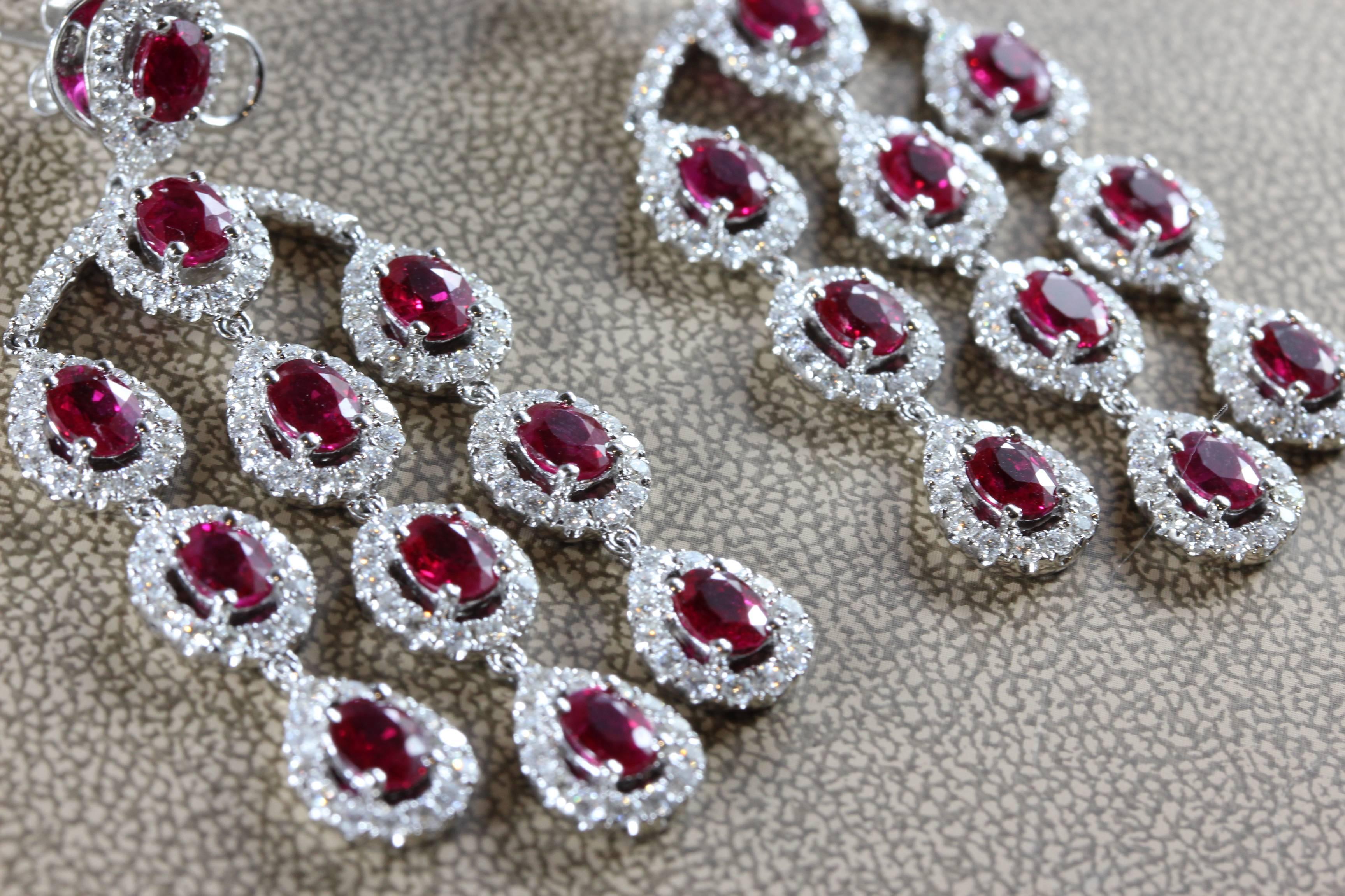 This spectacular pair of earrings feature 10.72 carats of fine vivid red pigeon's blood rubies in oval shape, which we believe to have Burmese origin due to their intense color. The rest of the earrings are studded with 3.87 carats of round cut