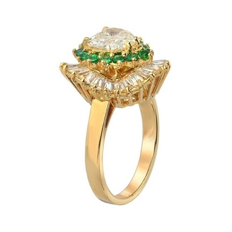 Queen of hearts! This ballerina style ring features a center heart shape diamond weighting 1.30 carats. It is surrounded by a dazzling halo of 0.50 carats of round cut emeralds and an external halo of baguette cut diamonds totaling 2 carats. Set in