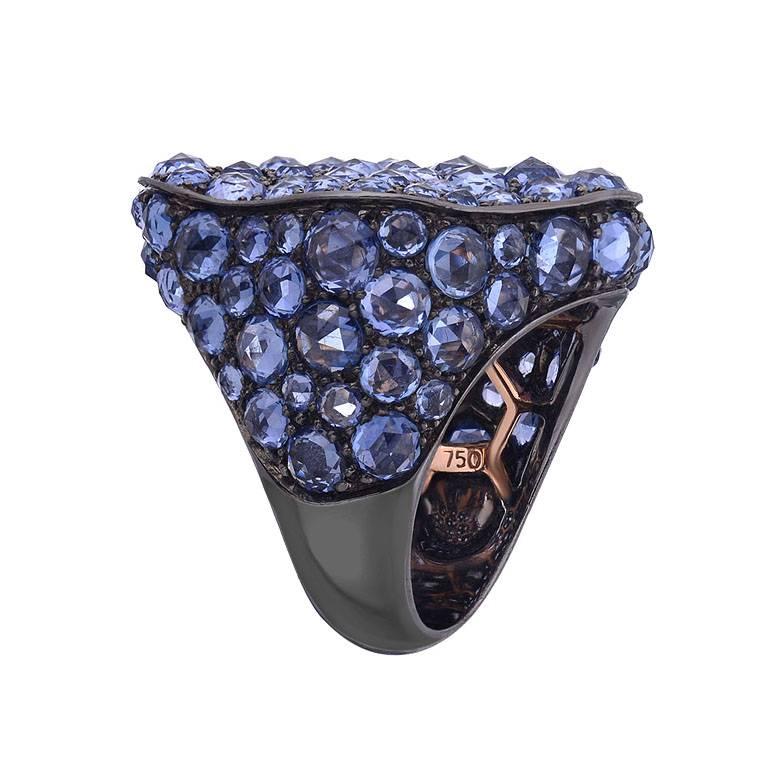 This ultra-glistening cocktail ring features 11.80 carats of rose cut blue sapphire set in 18K gold. The piece has a black rhodium finish which gives great contrast to the blue sapphire and give the ring an overall unique look.

Currently ring size