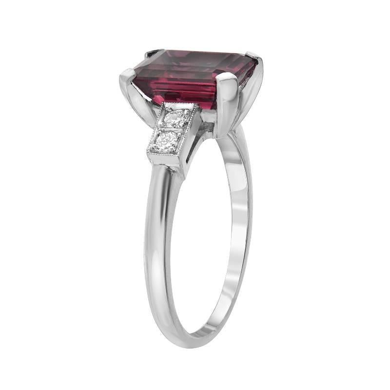This estate ring features a 4.00 carat pinkish red colored tourmaline, emerald cut. On the sides of the tourmaline gemstone are a total of 4 diamonds, VS clarity F-G color, weighing 0.10 carats. Made in platinum. 

Size 6.25 (Sizable) 