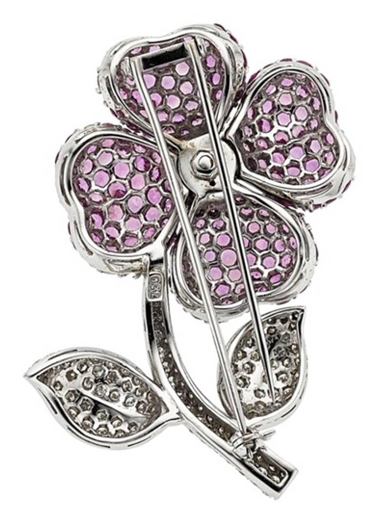 The brooch features round-cut pink sapphires weighing a total of approximately 13.30 carats, enhanced by full-cut diamonds weighing a total of approximately 2.25 carats, set in 18k white gold. Gross weight 30.20 grams.
Dimensions: 2-3/16 inches x