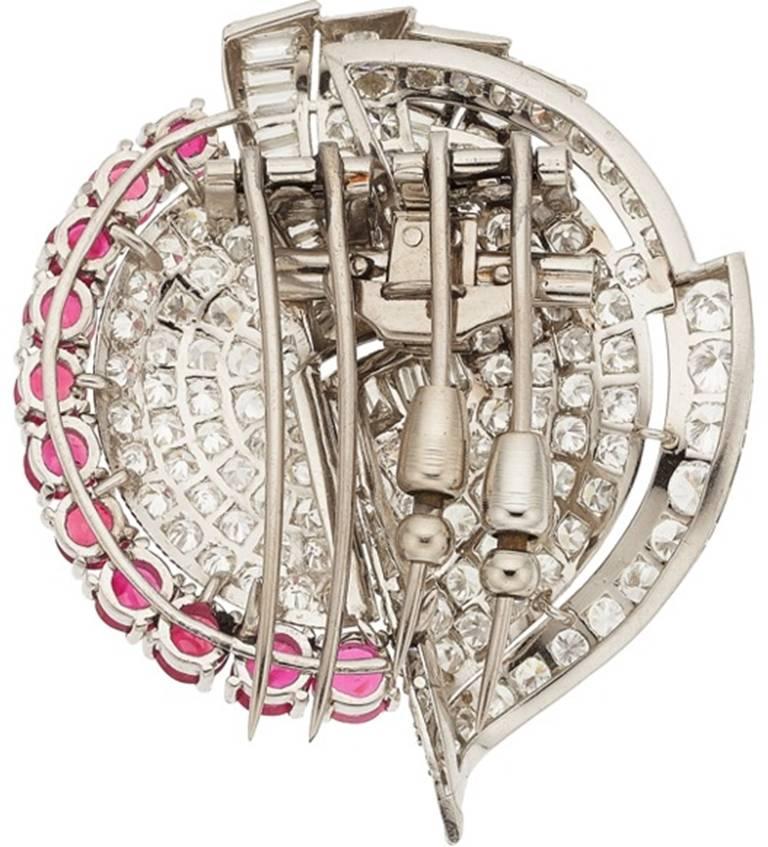 A spectacular platinum Art Deco double-clip-brooch featuring just under 10 carats of round and baguette cut diamonds. Accenting the one of the two clips are 11 rubies weighing a total of 5.40 carats, giving the brooch a flash of vivid red color.