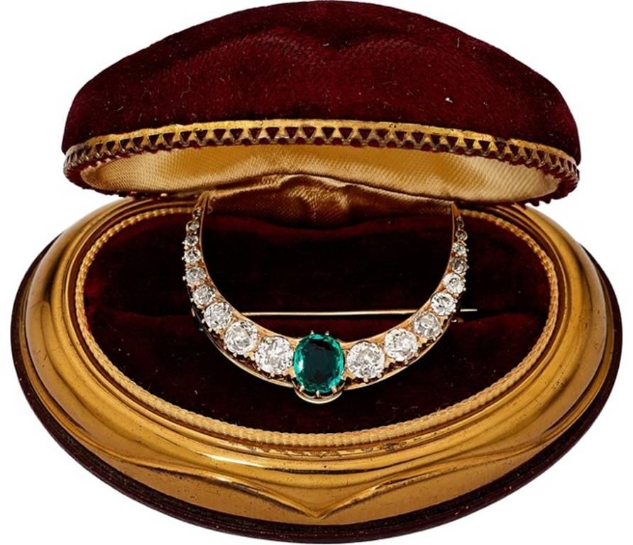 A stunning gold brooch featuring old-cut diamonds weighing a total of approximately 2.40 carats, enhanced by an oval-shaped emerald weighing approximately 0.80 carat, set in 18k gold. Gross weight 6.00 grams.
Dimensions: 1-5/16 inches x 1-1/16 inches