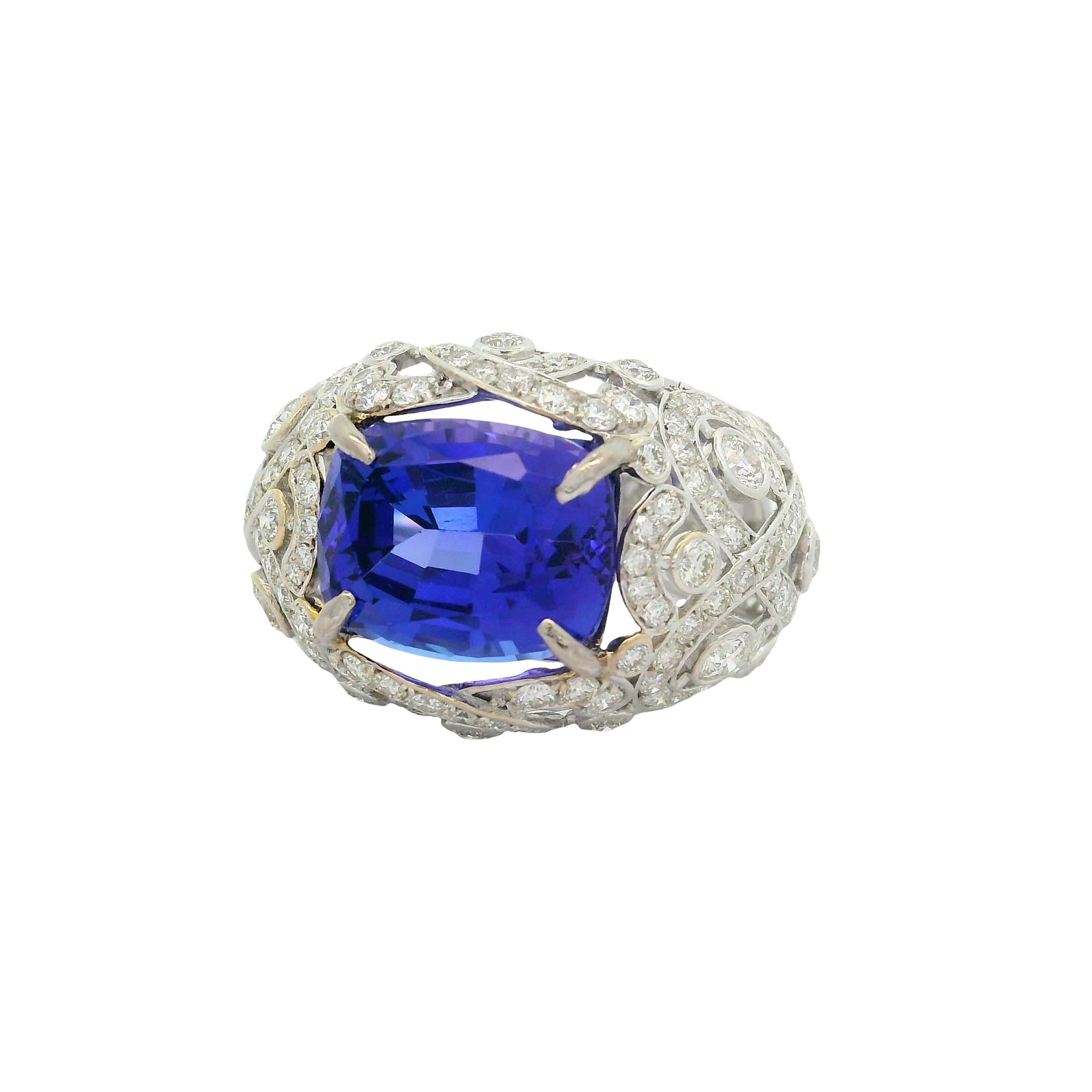 A stunning cushion-cut brilliant tanzanite, weighing 7.49 carats, commands attention at the center of this contemporary ring. The tanzanite's vivid blue-purple color is both striking and mesmerizing. Encircling the centerpiece are round-cut white