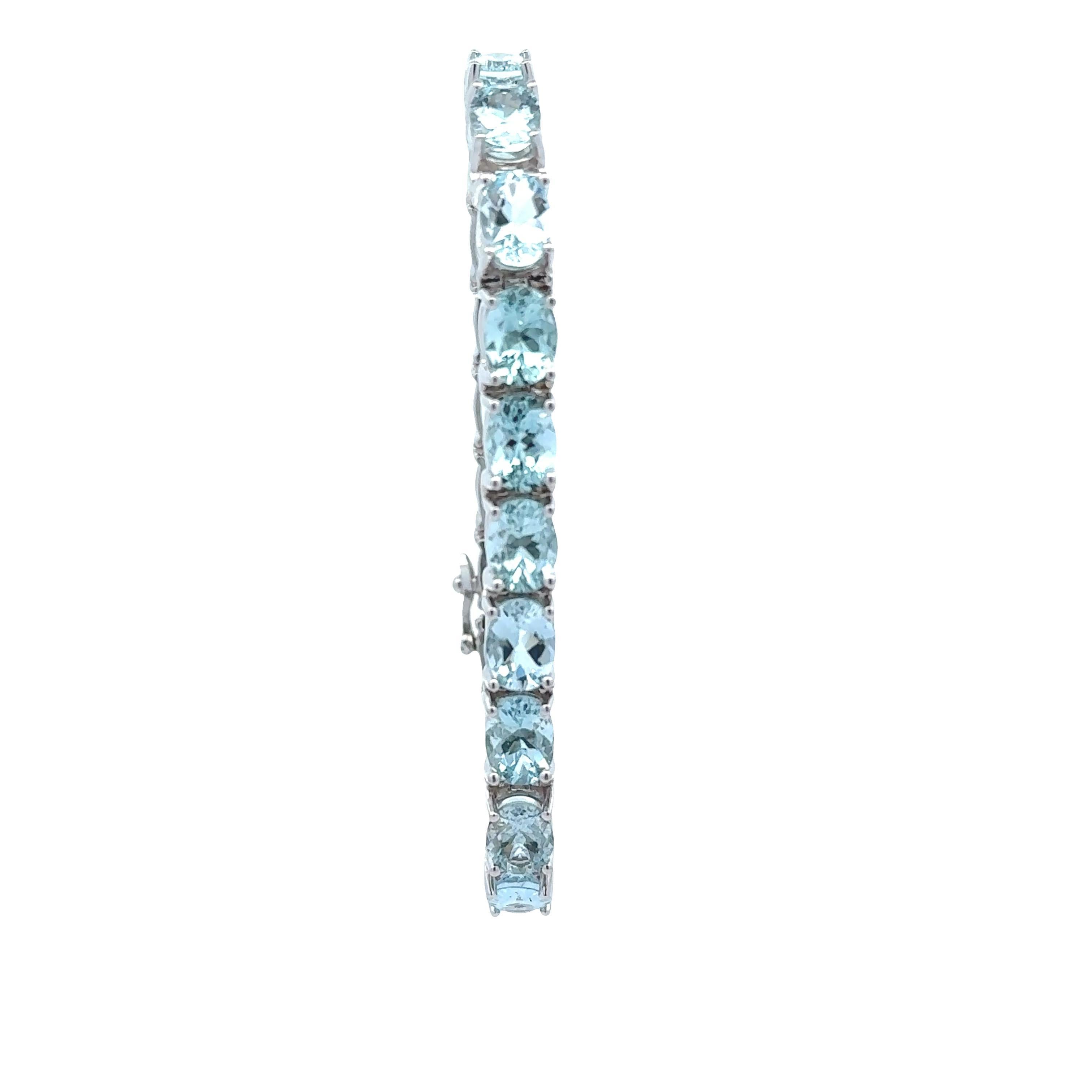 Una pulsera de tenis contemporánea, con un diseño estilizado y elegante. La pulsera está adornada con aguamarinas de talla ovalada que suman aproximadamente 50,00 quilates y ofrecen un cautivador tono azul. Elaborada en oro blanco de 14 quilates, la