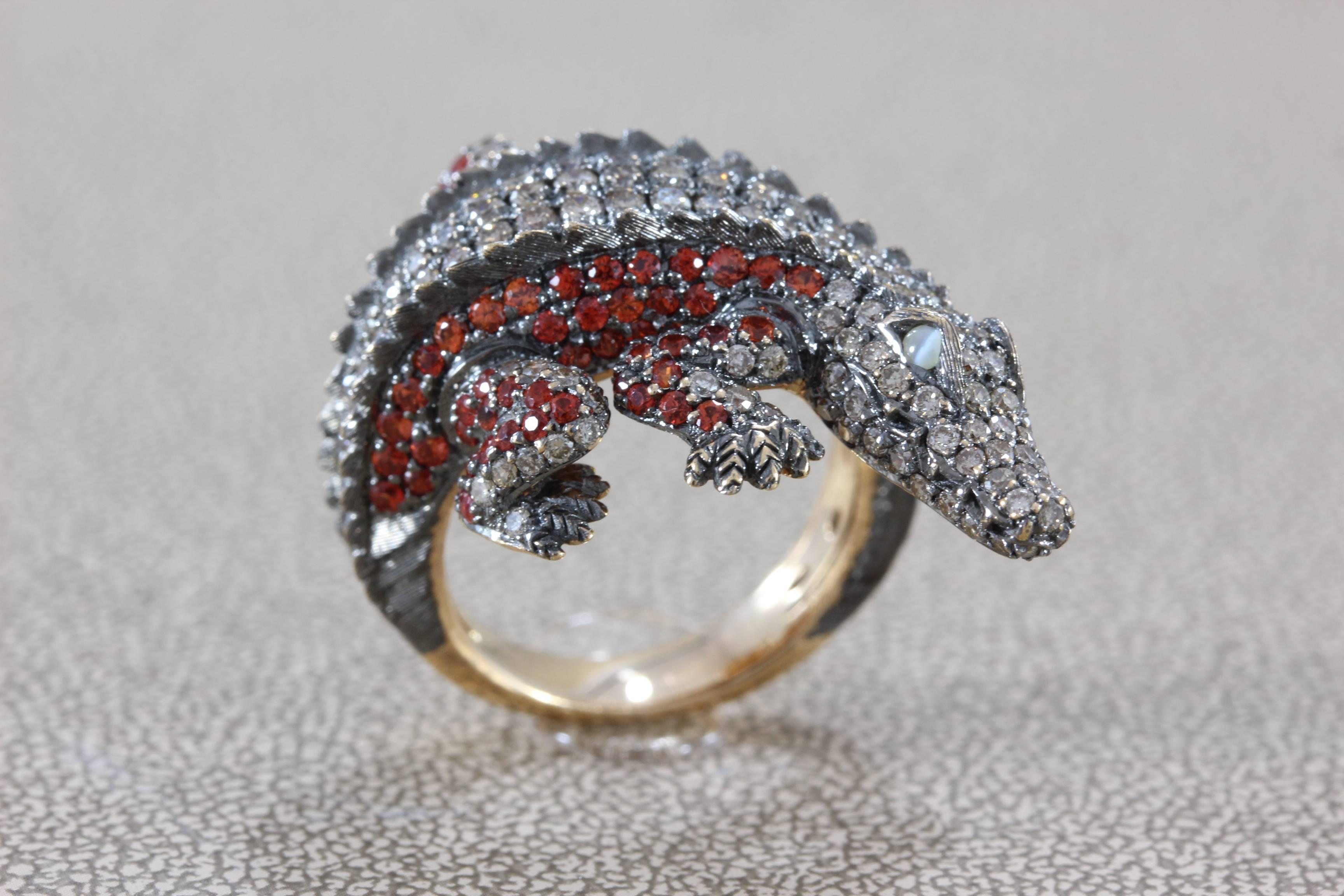 A spectacular fun and sexy gator ring featuring fancy colored diamonds and orange sapphire set in 18K gold. The eyes of this fearsome creature are cat eyes with strong bands that move in the light bringing the piece to life.

Dimensions: 1.25 x 1.00