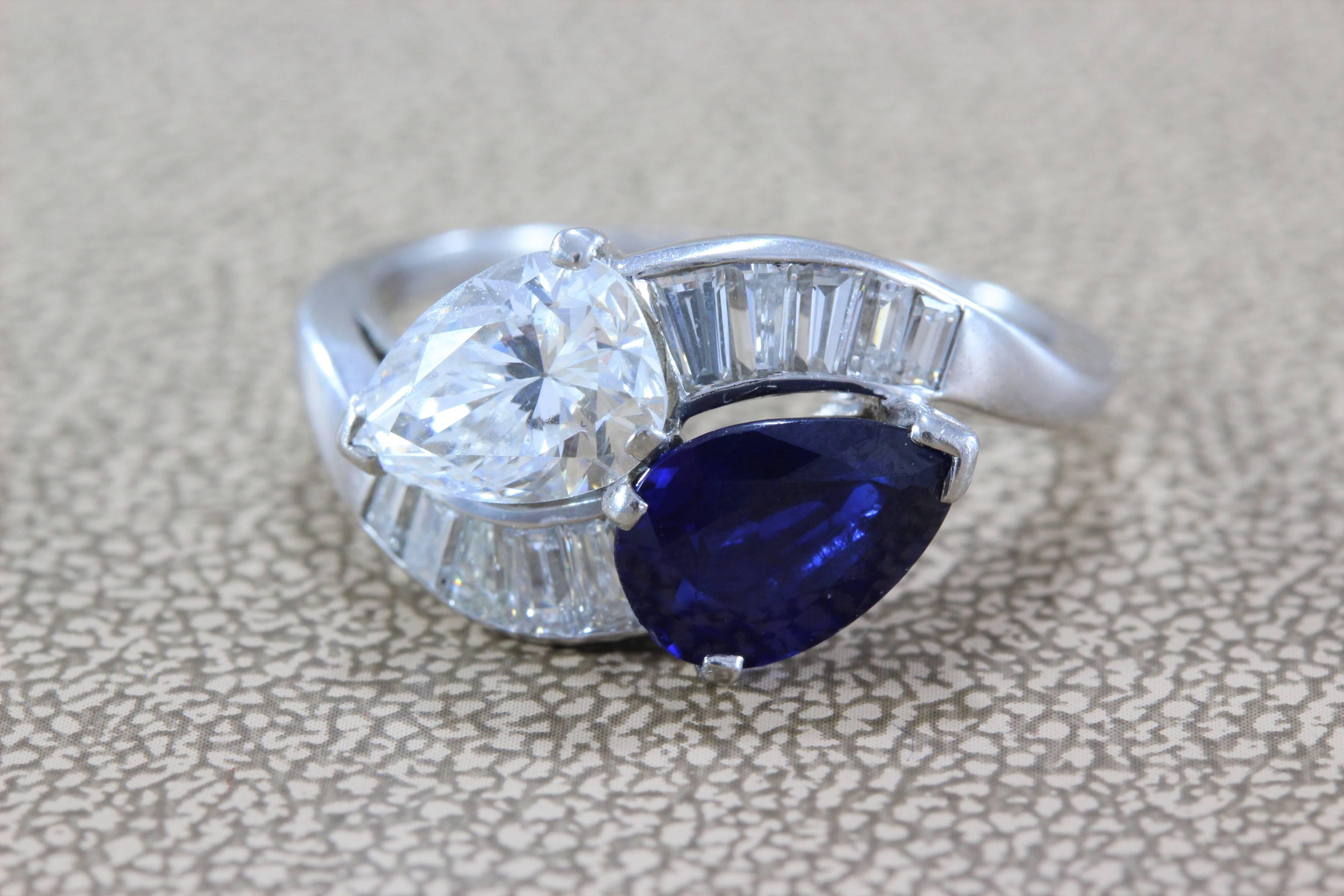 A stunning sleek bypass ring featuring a 1.27 carat GIA Certified pear shape diamond, F/SI1, and a 1.30 carat richly colored blue pear shape sapphire. Diamond baguettes accent the two stones, all set in platinum. 

Two ways to wear the ring, diamond