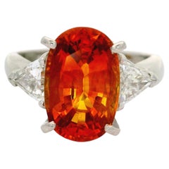 Anillo de tres piedras de platino con zafiro naranja de 5,91 quilates y diamantes, certificado por el GIA