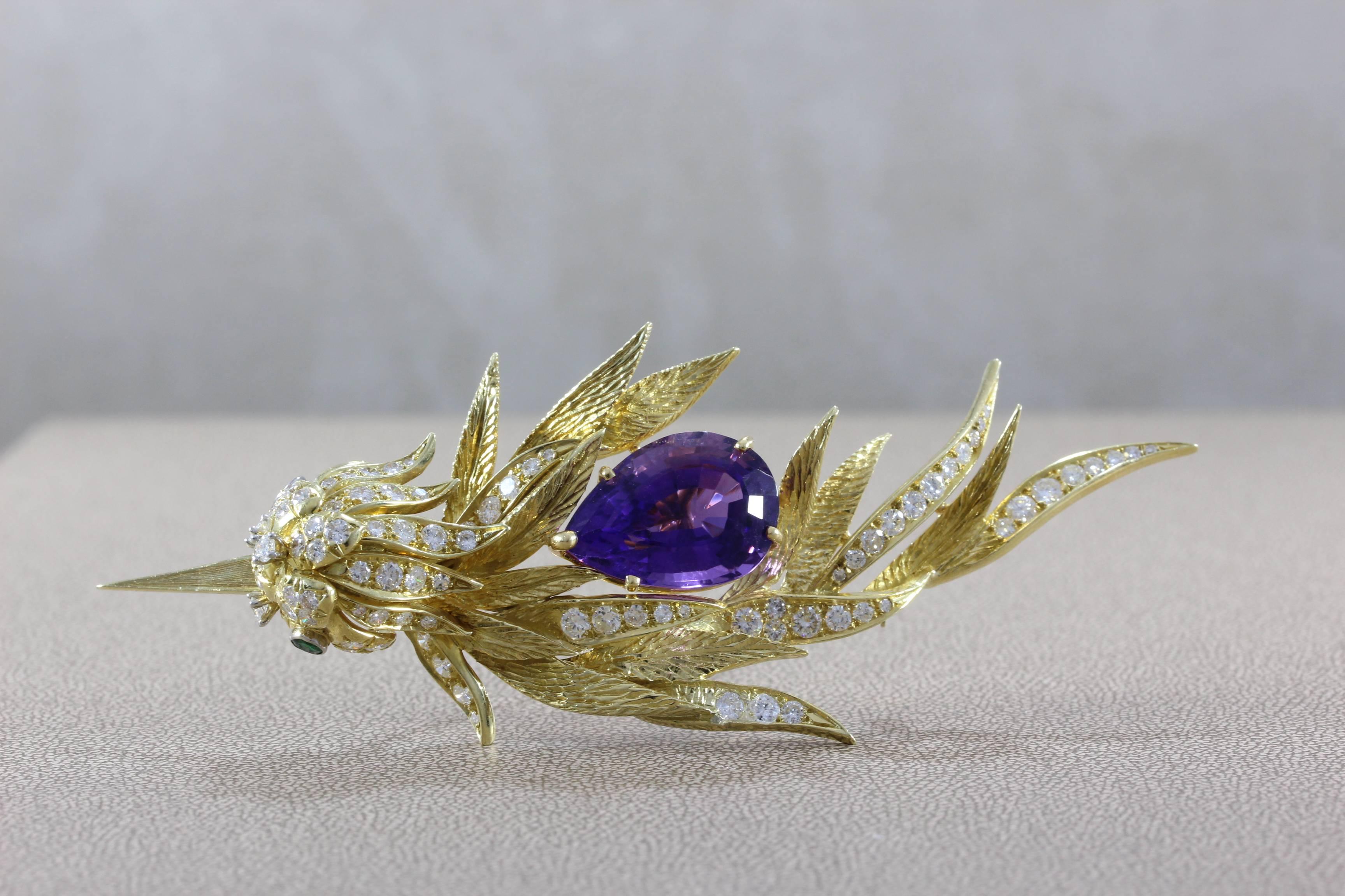 A creative work of art, this brooch features a 17.90 pear shape purple amethyst. Accenting the amethyst and creating flair to the piece are 4.07 carats of diamonds set in 18K yellow gold on the feathers and head of the lovely bird. Two emeralds act