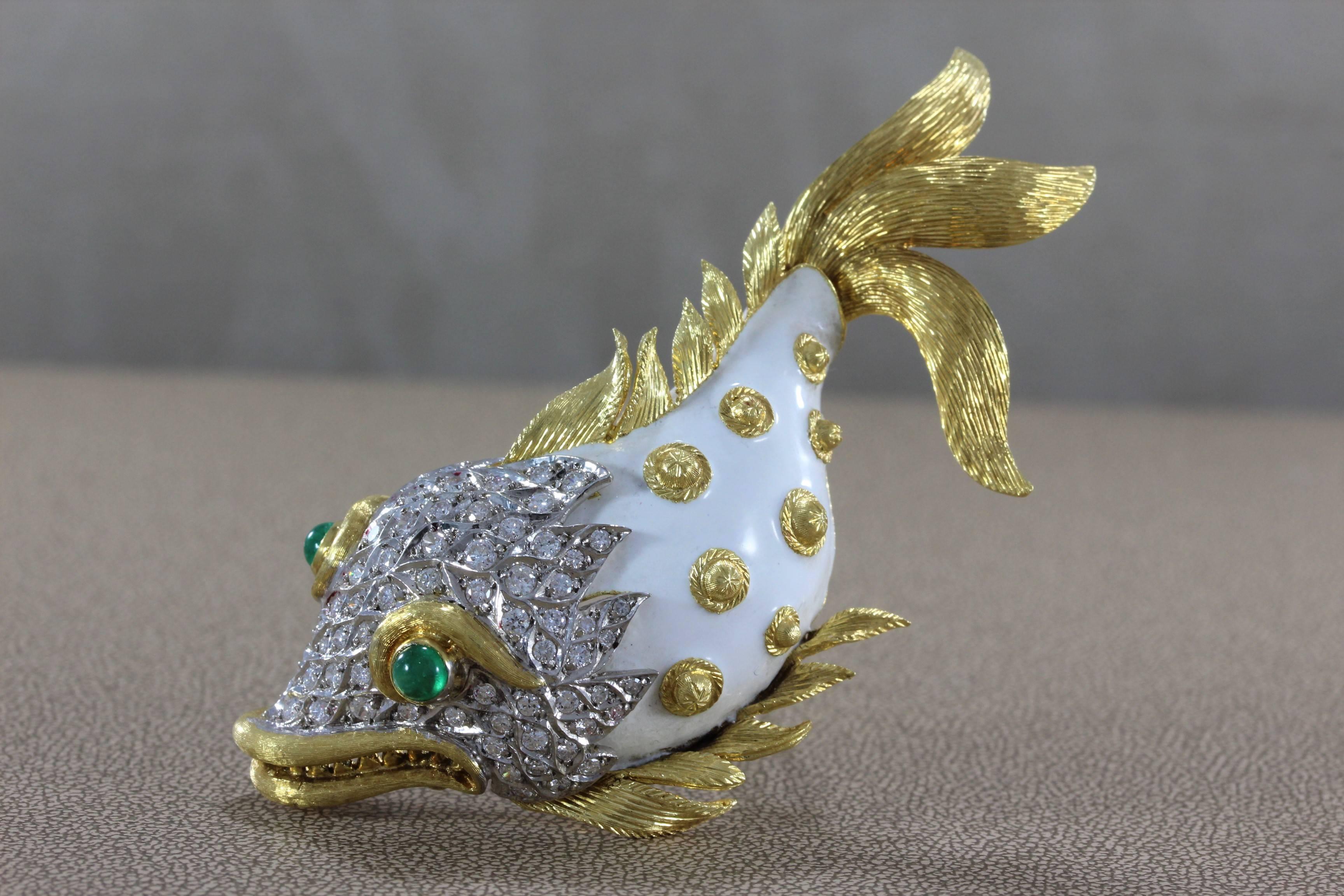 A lovely fish studded with 3.23 carats of diamonds set in 18K gold. Smooth white enamel is used on the fish's body with gold accents making it unique. Two emerald cabochons act as its mesmerizing eyes. 

Dimensions: 3.5 x 1.5 inches