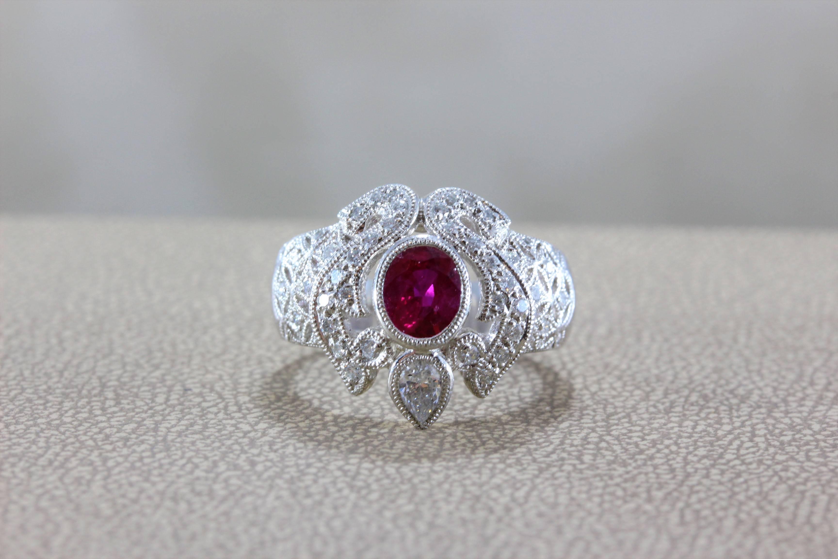 A beautiful platinum ring featuring a vivid red oval shaped ruby, weighing 0.92 carats, which we believe to have a Burmese origin. A larger pear shape diamond along with rounds accent the center stone, set in platinum with milgrain settings. 

Size