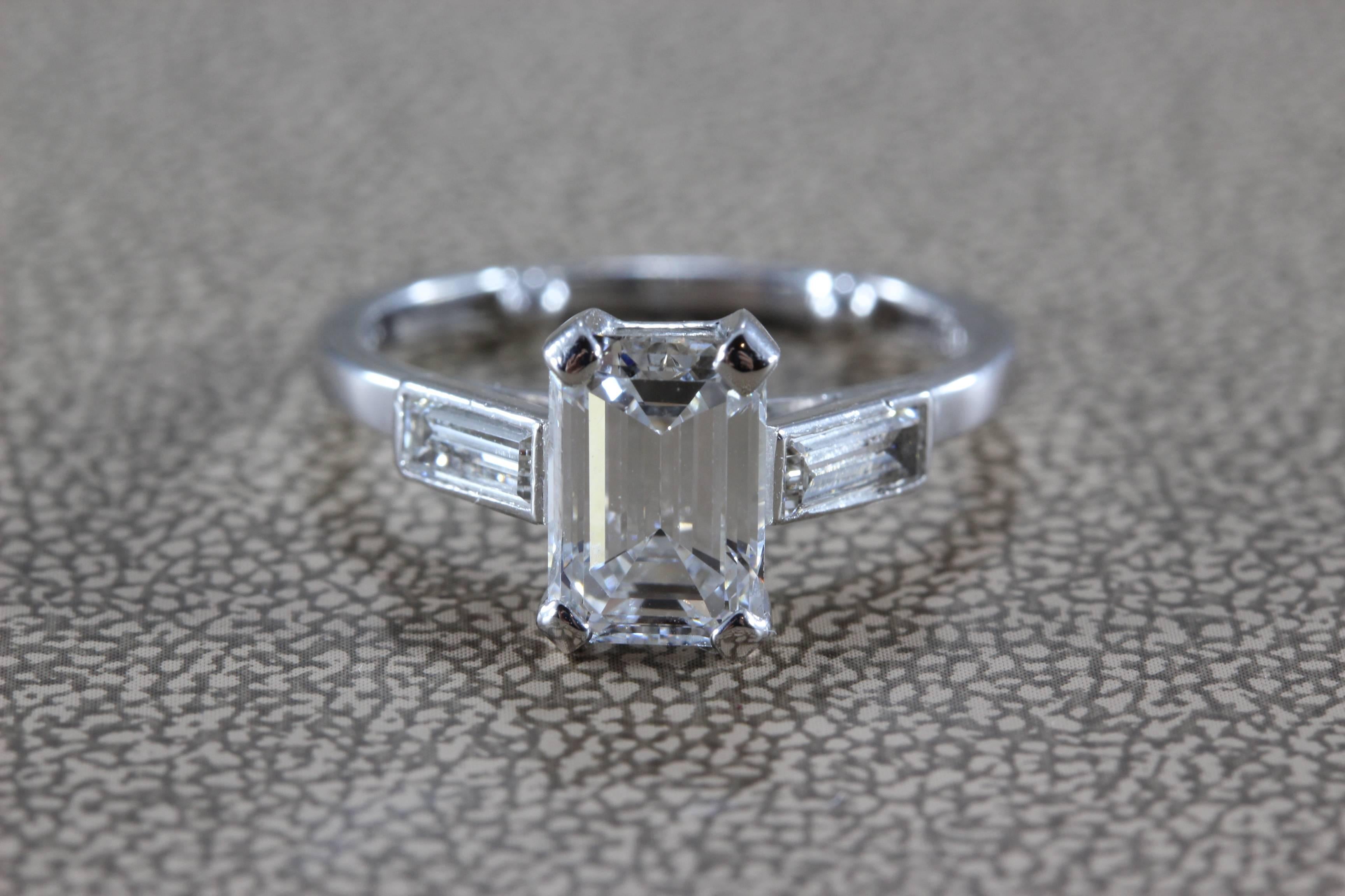 A classic diamond engagement ring by the King of Diamonds, Harry Winston. It mains a beautifully cut and shaped 1.38 carat E VS1 emerald cut diamond, top color and clarity.  Two baguette cut diamonds of equal quality are set on the shoulders of the