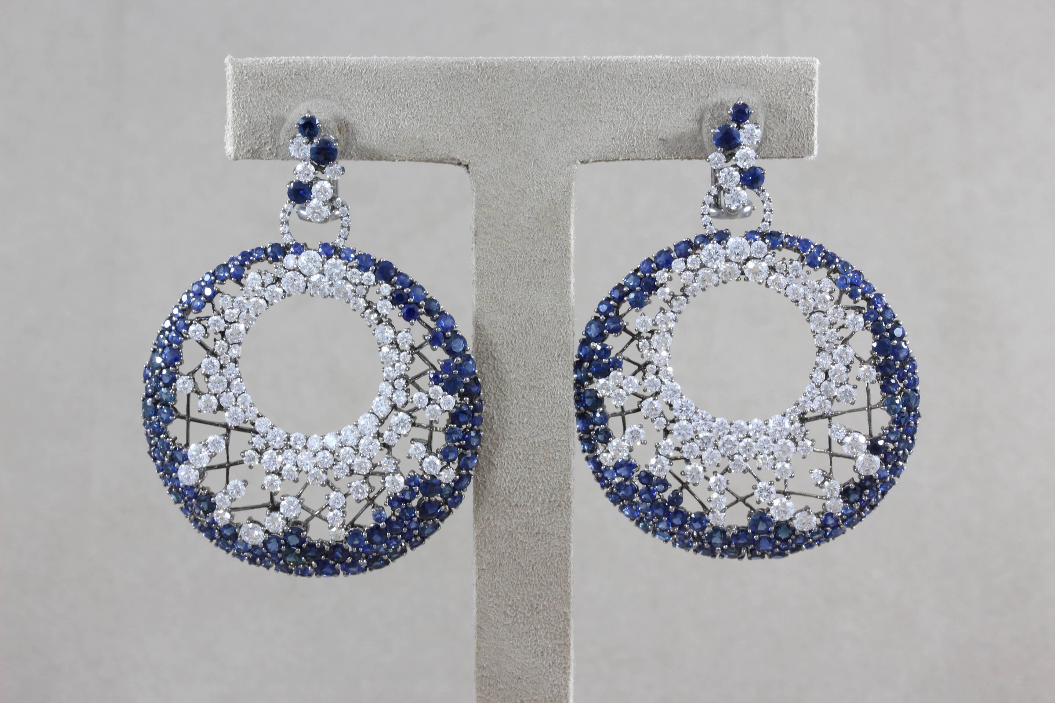A spectacularly designed pair of earrings featuring top quality round cut diamonds and blue sapphires which are set in 18K black gold. The earrings feature 9.80 carats of VS quality round cut diamonds and 12.76 carats of beautiful vivid blue