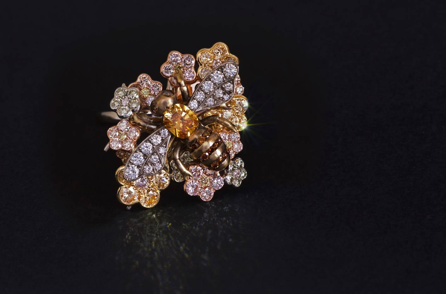 Delightful dress ring with Bee sitting on a flower bed. The Bee's body is a 0.28ct Fancy Vivid Yellowish Orange Diamond ( GIA Cert ) of SI1 clarity. Three rows of Champagne Diamonds form the strips in its abdomen and an upside down Diamond its sting