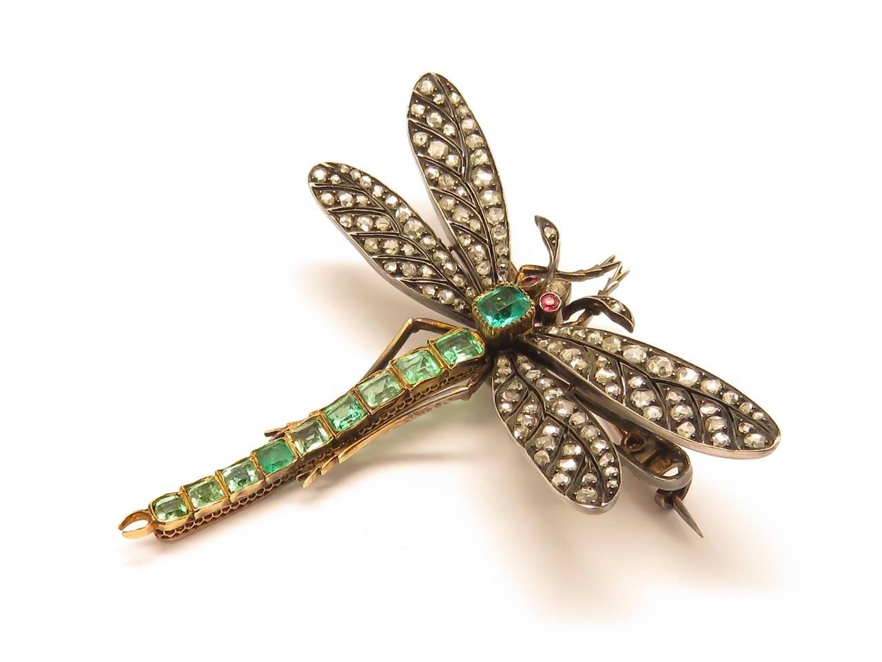 Delicate silver on gold Art Nouveau period with calibre cut emeralds set in the tail and ruby set eyes , set with  old cut diamonds mounted in 18k gold and silver.
French make.
Measurements Approximately:  61 x 61 mm  
Height: 24 inches
Width: 24