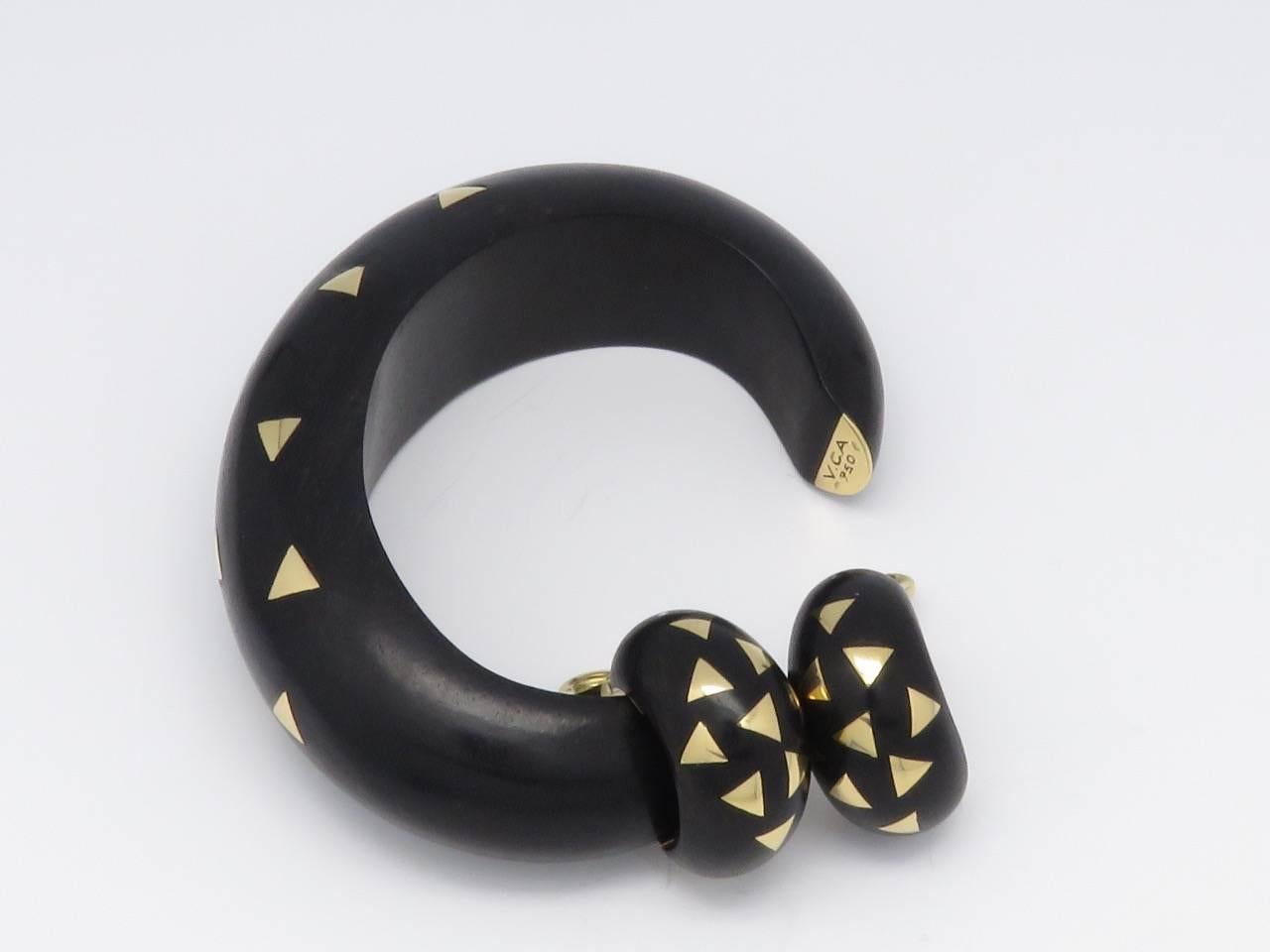 The open bangle bracelet and pair of earrings is composed of carved ebony with inlayed 18 K gold triangles.
Bracelet signed VCA 750 and numbered B2587D12
Earrings signed VCA and numbered B3502D12 750
French assay marks.
Circa