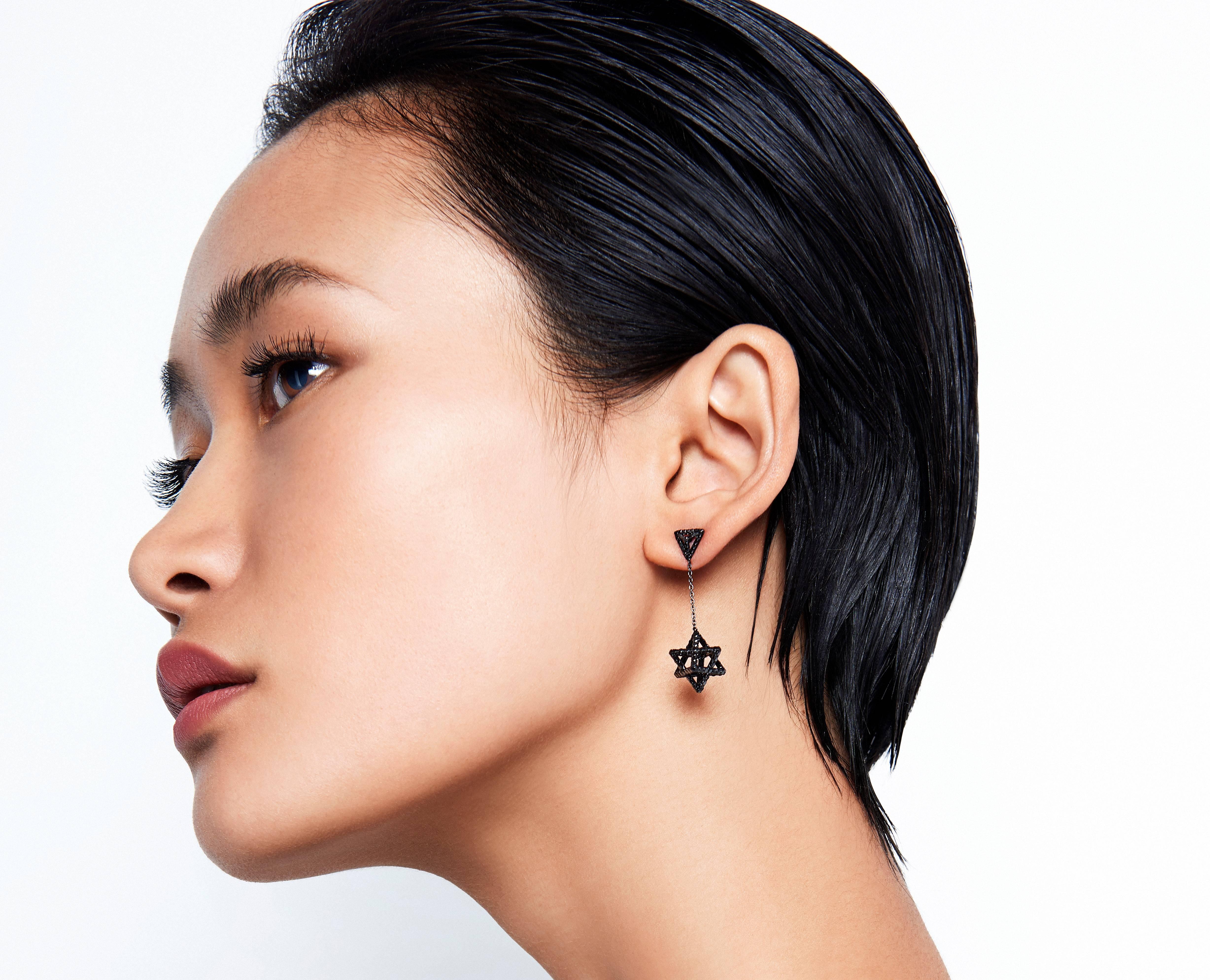 Merkaba black-finished platinum drop earrings, tethered by a triangle stud, feature a single chain suspending a Merkaba star measuring 0.57 inches. Set with a total of approximately 2.07 carats of round brilliant black diamonds. Secure screw backs