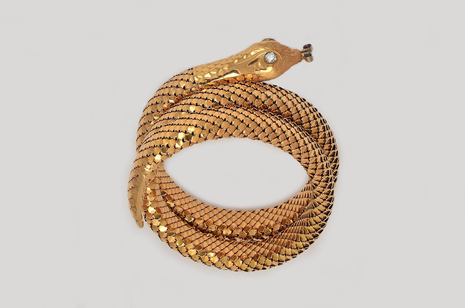 An elegant retro Snake Bangle Bracelet made of 18 Kts. Yellow Gold with scaled chain body. Set with brillant cut-diamonds in its eyes and red stones in its nose. This bracelet has three coils.