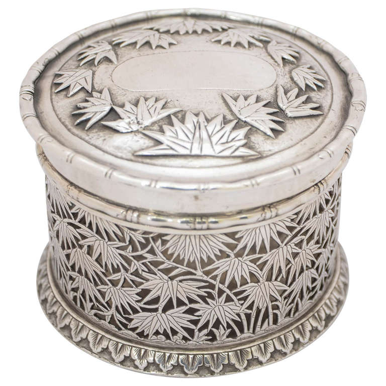 A Chinese Export Silver Box of round form, pierced sides, and pull-off lid. The decoration is of bamboo and there is a plain shield on the cover. The box is heavier than is usual for this type, weighing 216gms. It is 6.5cms high and the diameter is