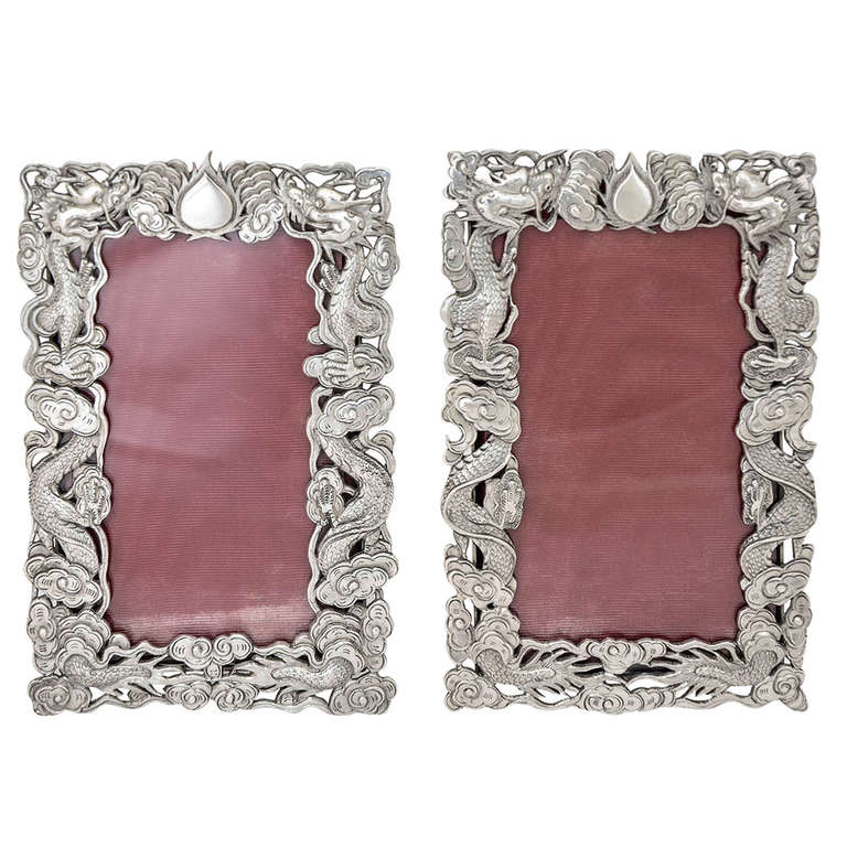 A pair of Chinese export silver photo frames, each with a border of two coiled opposing dragons separated by a flaming pearl, and with the easel supports engraved to simulate bamboo. The frames were made by the well known Hong Kong firm of Wang Hing