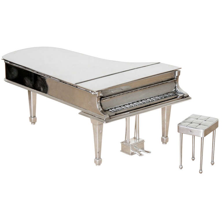 This delightful silver grand piano and stool was made by Theo fennell and hallmarked London 1993. The lid can be raised and the piano used as a trinket or jewel box. The length of the piano is 16.5cm