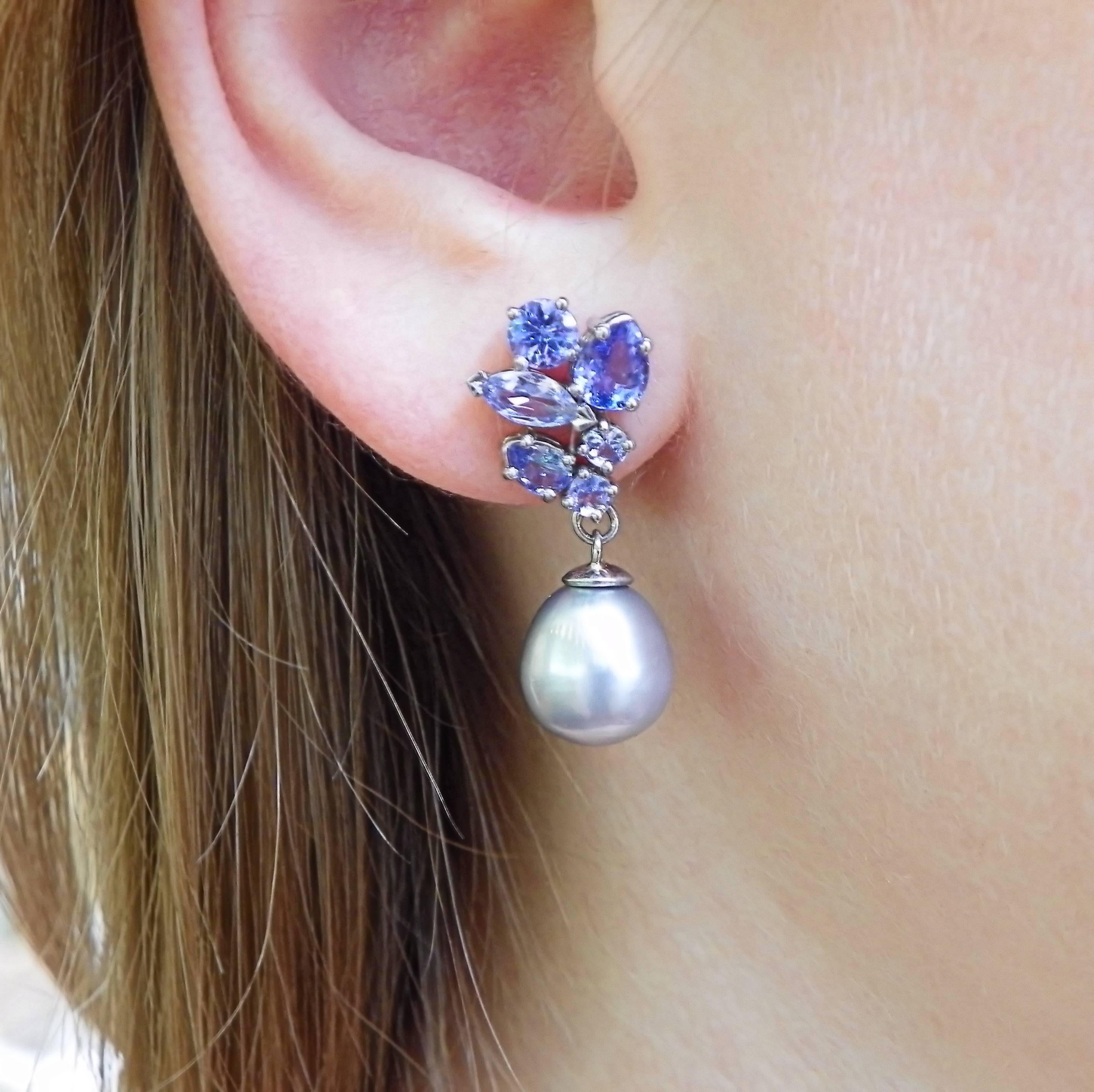 Gorgeous and unique dangling cluster drop earrings with silver pearshaped freshwater pearls and tanzanites. These lovely new earrings feature each a classic yet modern cluster with 6 tanzanites. The 14K white golden pearl drop earrings sparkle and