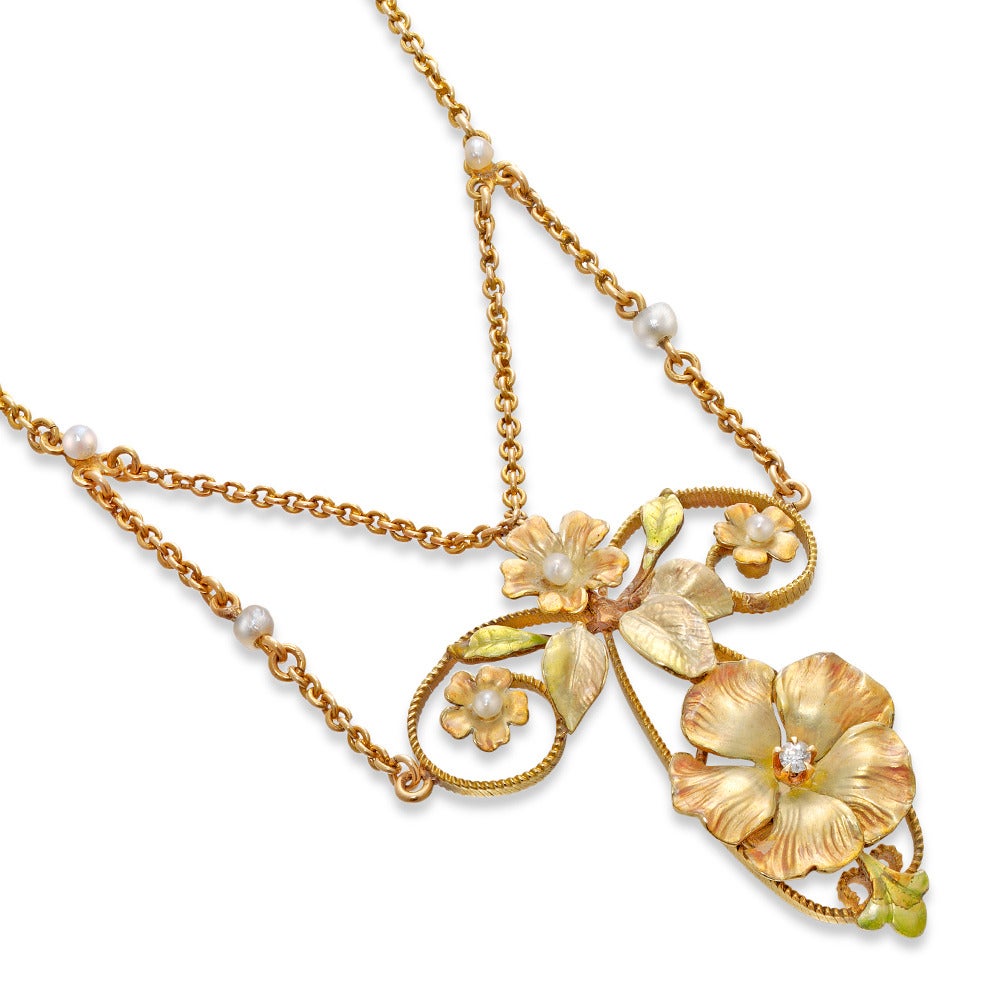 An Art Nouveau enamel floral necklace, comprising a main flower embellished with an old brilliant-cut diamond to the centre, with a surmount of three further flowers with natural pearl centre and foliate motifs, the finely modelled petals and leaves