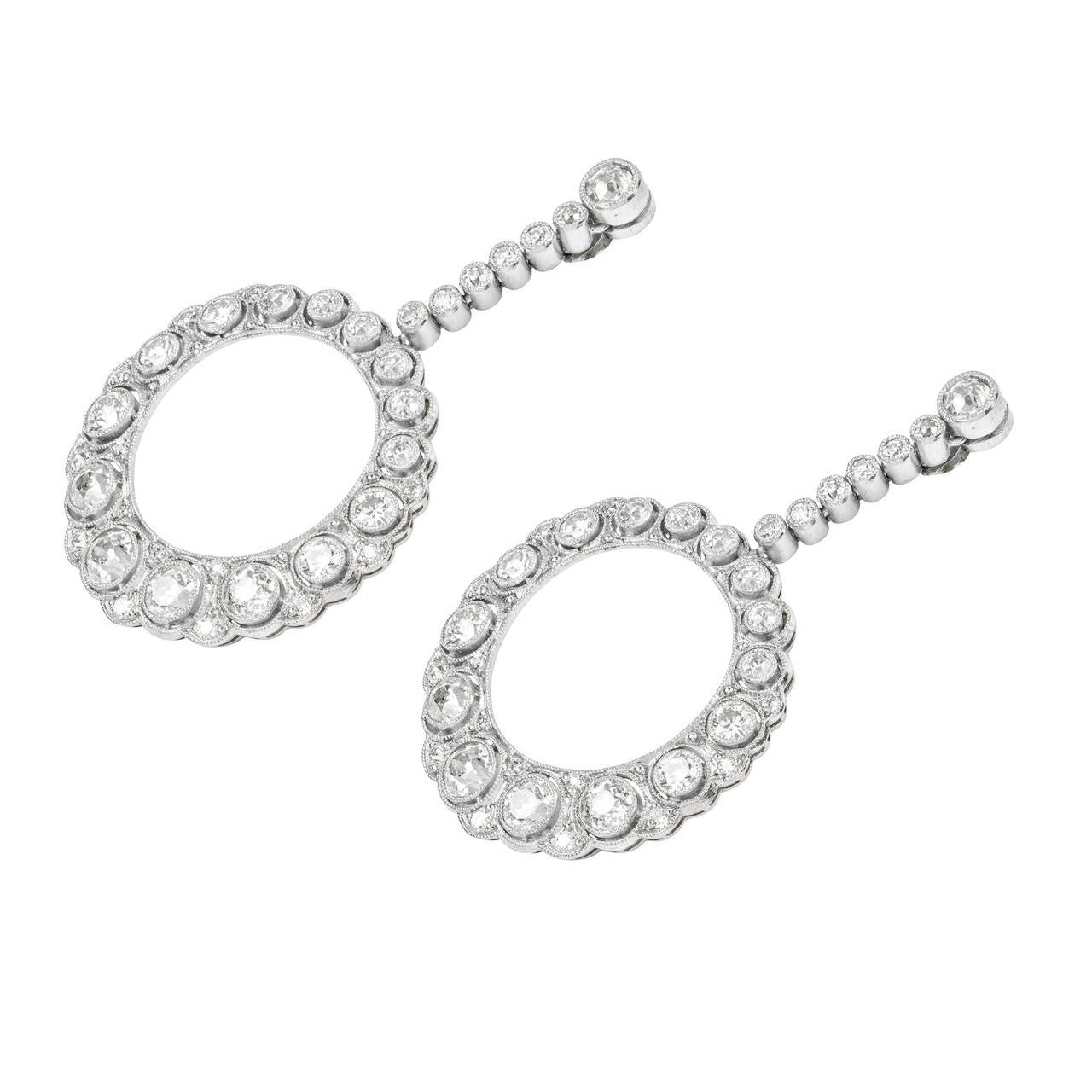 A pair of early 20th-century diamond-set hoop drop earrings, each earring consisting a graduated pierced hoop set with old brilliant-cut diamonds suspended from six diamonds and an old brilliant-cut diamond top, estimated to weigh a total of 2