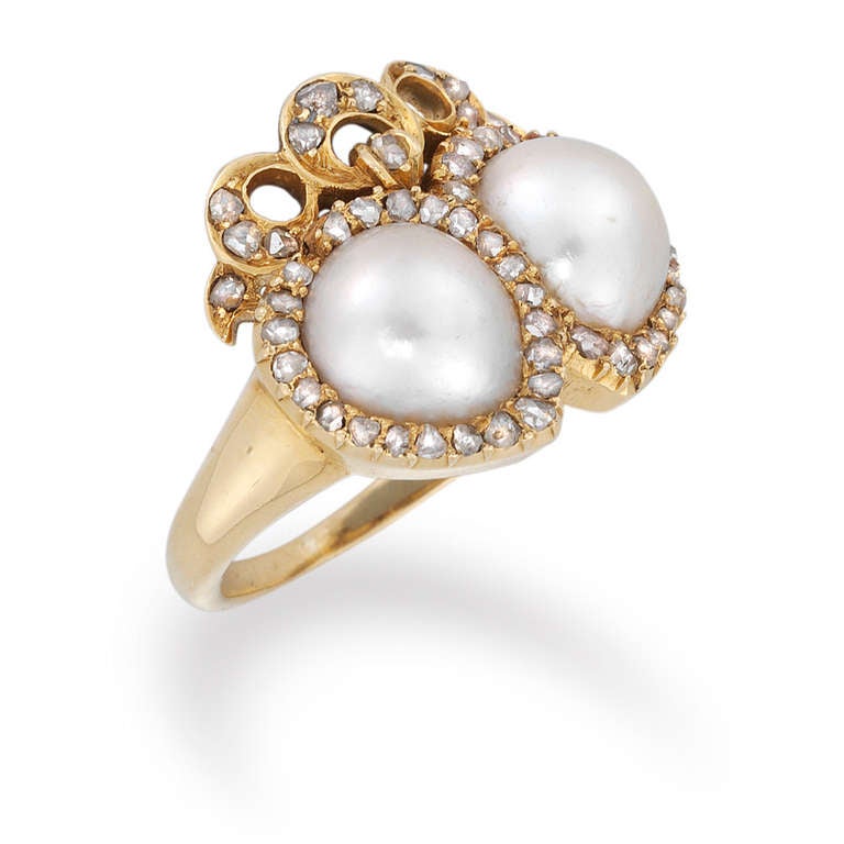 A late Victorian natural pearl and diamond twin heart ring, the ring comprising two interlocking hearts, each set to the centre with a natural pearl to a rose-cut diamond-set border, with diamond-set bow surmount, all grain-set to a yellow gold