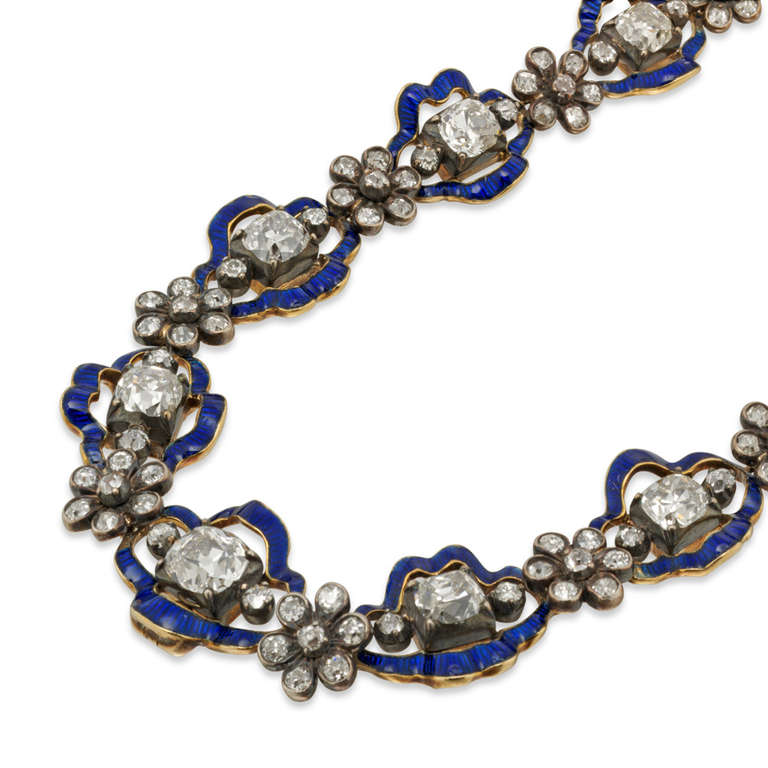 A magnificant Regency diamond and blue enamel cluster necklace, the necklace comprising twenty-two diamond and enamel cluster motifs, each set with an old cushion-cut diamond with a single-cut diamond to each side, all within a wavy blue enamel