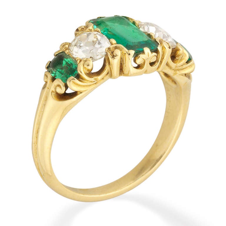 A late Victorian emerald and diamond five-stone ring, the ring set with three emerald-cut emeralds, estimated to weigh a total of 1.30 carats, alternately-set with two old-cut diamonds, estimated to weigh a total of 0.80 carats, all claw-set to an