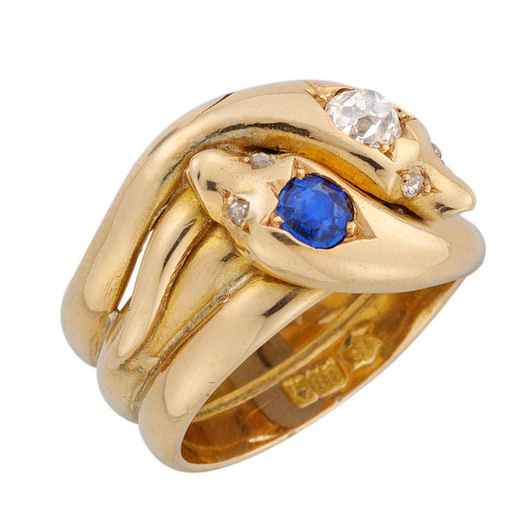 A Victorian twin snake ring, the ring comprising two entwined yellow gold serpents, the heads set with an old brilliant-cut diamond estimated to weigh 0.25 carats and a round faceted sapphire weighing approximately 0.25, with rose-cut diamond-set
