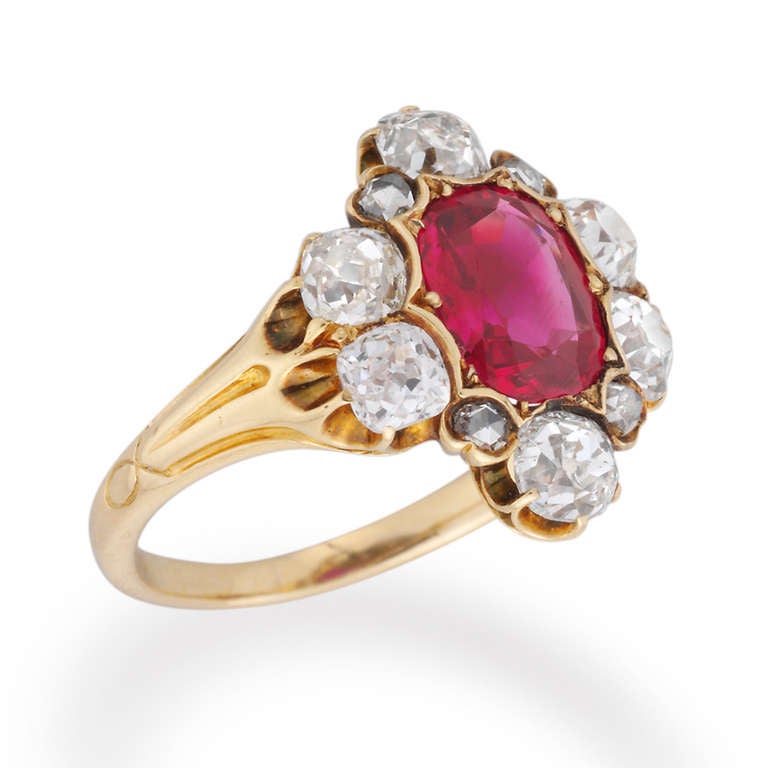 A Late Victorian ruby and diamond cluster ring, the oval faceted ruby weighing approximately 2 carats, yellow claw-set to the centre of a cluster  surround of ten old brilliant-cut and rose-cut diamonds, estimated to weigh a total of 1.7 carats, all