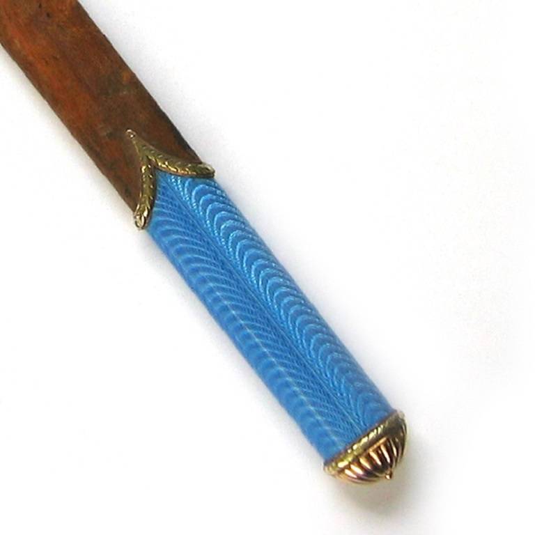 An important Faberge enamel and wooden paper knife, the wooden paper knife embellished with a blue enamel guilloche enamel handle with engraved rose gold fluted domed termination with yellow gold wreath border, gross weight 45 grams, circa 1900.