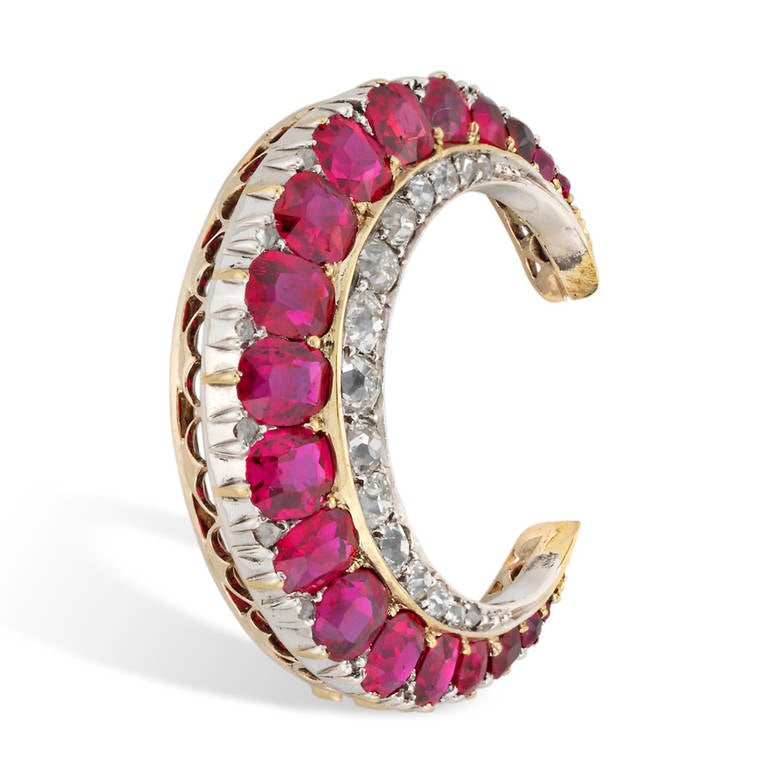 A Victorian ruby and diamond crescent brooch, with one row of cushion-cut graduating rubies estimated to weigh approximately 3 carats and a row of graduating old brilliant-cut diamonds weighing approximately half a carat, all set in silver to a