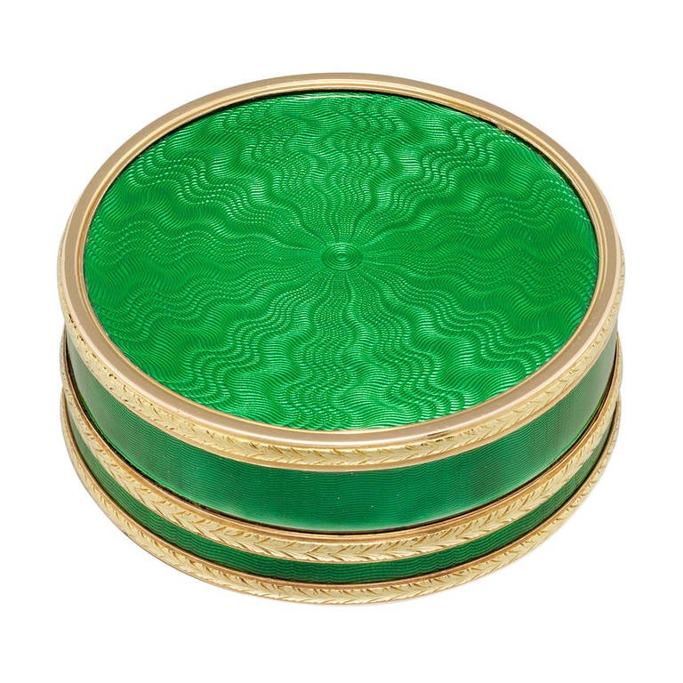 An early twentieth century Faberge circular green enamel silver-gilt and gold pill box, the translucent grass green enamel upon an engine-turned guilloche ground with radiating pattern, all in silver, applied bands of rose and yellow gold laurel