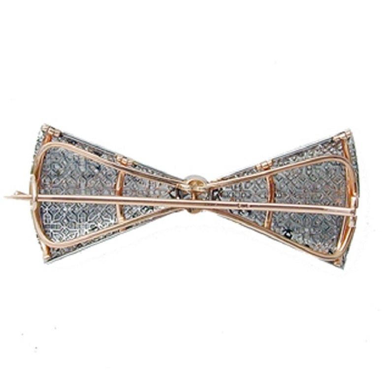A Fabergé diamond bow brooch, unsigned, the central brilliant-cut diamond with the bow of pierced platinum work in cross designs set with rose-cut diamonds all millegrain set in platinum on a gold frame, with detachable brooch fitting, St Petersburg