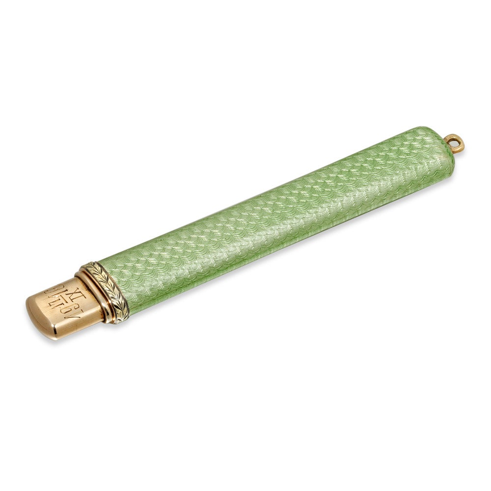 A Fabergé enamel pencil holder, the pale green guilloché enamel case, with termintaing in a yellow gold band with engraved foliate detail, the yellow gold pencil mount engraved 