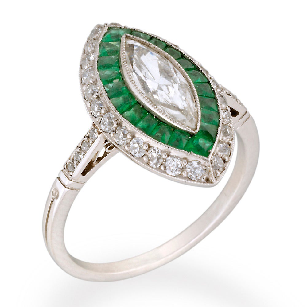 An emerald and diamond double cluster ring, the marquise-cut diamond weighing 0.82 carats, millegrain rubover set to the centre of a calibre-cut emerald cluster surround, all within a border of old-cut diamonds, millegrain-set to in platinum with