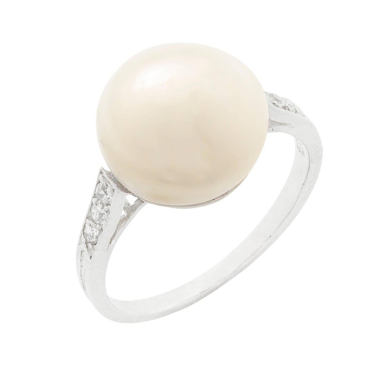Anillo de perla natural en forma de bouton con hombros engastados con diamantes, la perla blanca en forma de bouton mide aproximadamente 10,5 mm de diámetro en el centro de tres diamantes antiguos talla brillante engastados en cada hombro, hacia