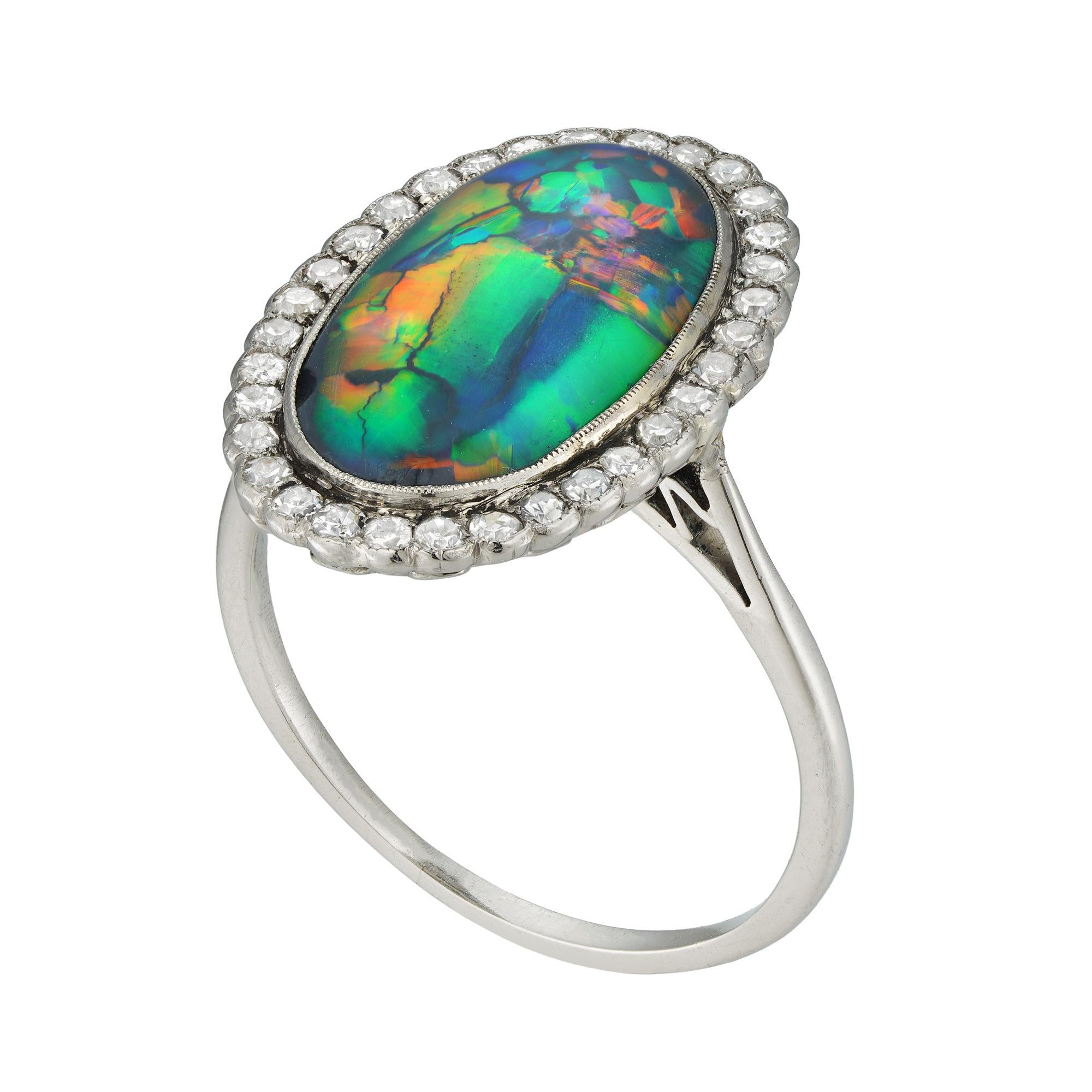 An Edwardian opal and diamond cluster ring, the oval cabochon-cut opal measuring approximately 16x9mm, surrounded by thirty-two single-cut diamonds estimated to weigh 1/3 carats, all millegrain-set in platinum mount with openwork gallery, to