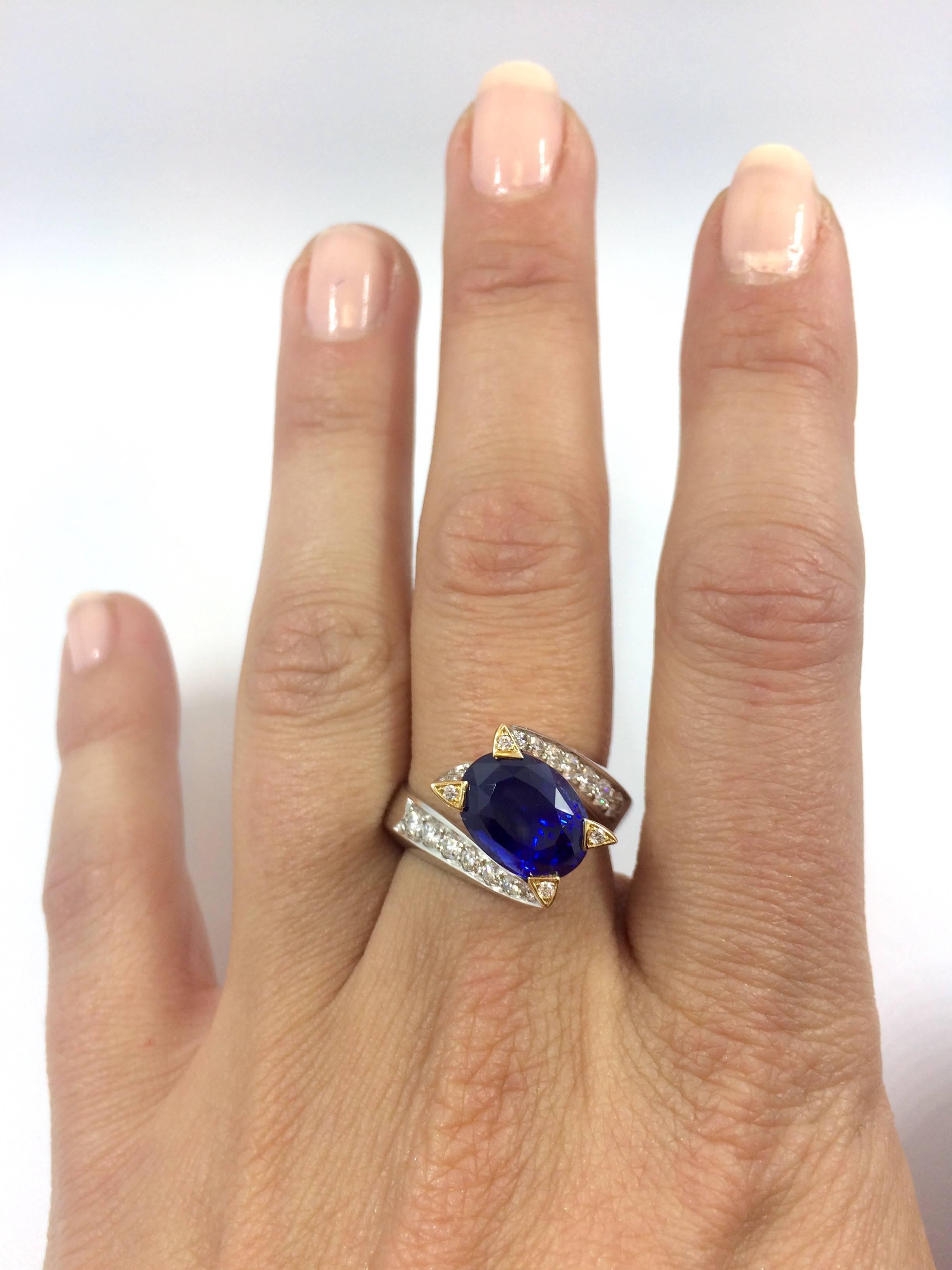A unique white and yellow gold ring set with an exceptional and rare unheated Burma Royal Blue oval sapphire. The sapphire is surrounded by 20 brilliants cut diamonds set on the body of the twisted ring. As well as four brilliant cut diamonds are