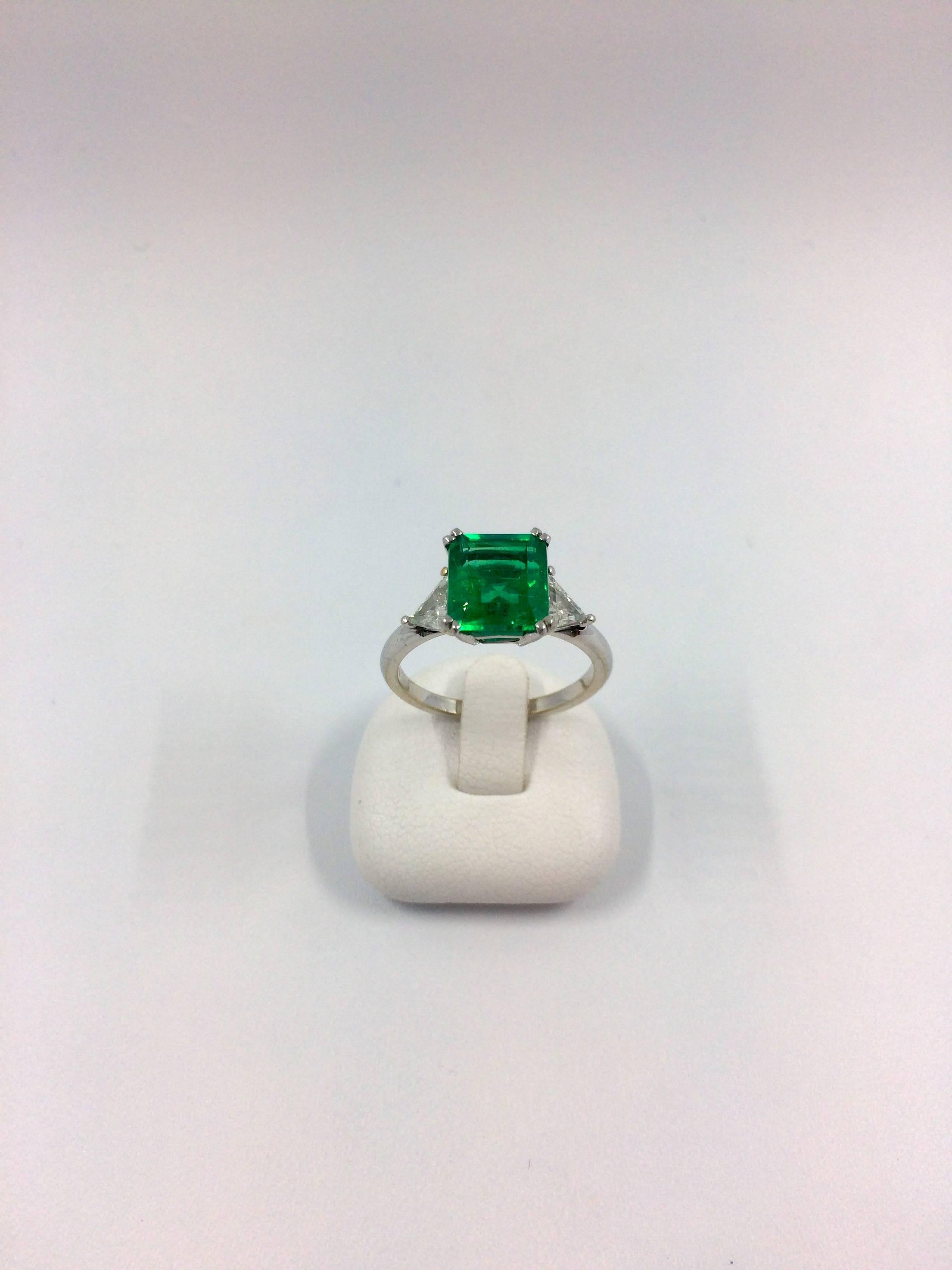 A white gold ring set in the middle with a 2.79 carat square colombian emerald. The emerald is flanked by two trillium cut diamonds.
- Emerald Weight: 2.79 carat
- Emerald Quality: no resin
- Total Diamond Weight: 0.49 carat
- Diamonds Quality: